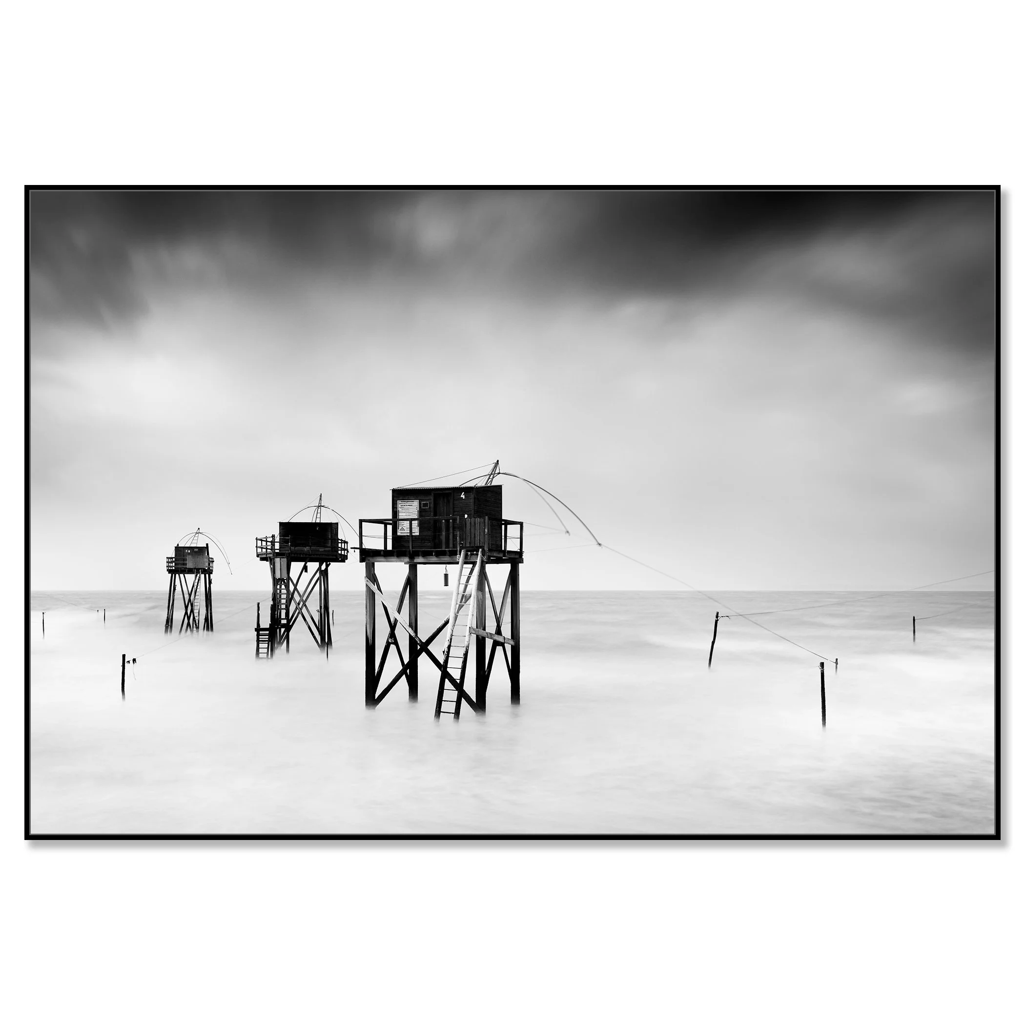 Monochrome long-exposure seascape with wooden fishing huts on stilts and misty water – framed ArtBox black