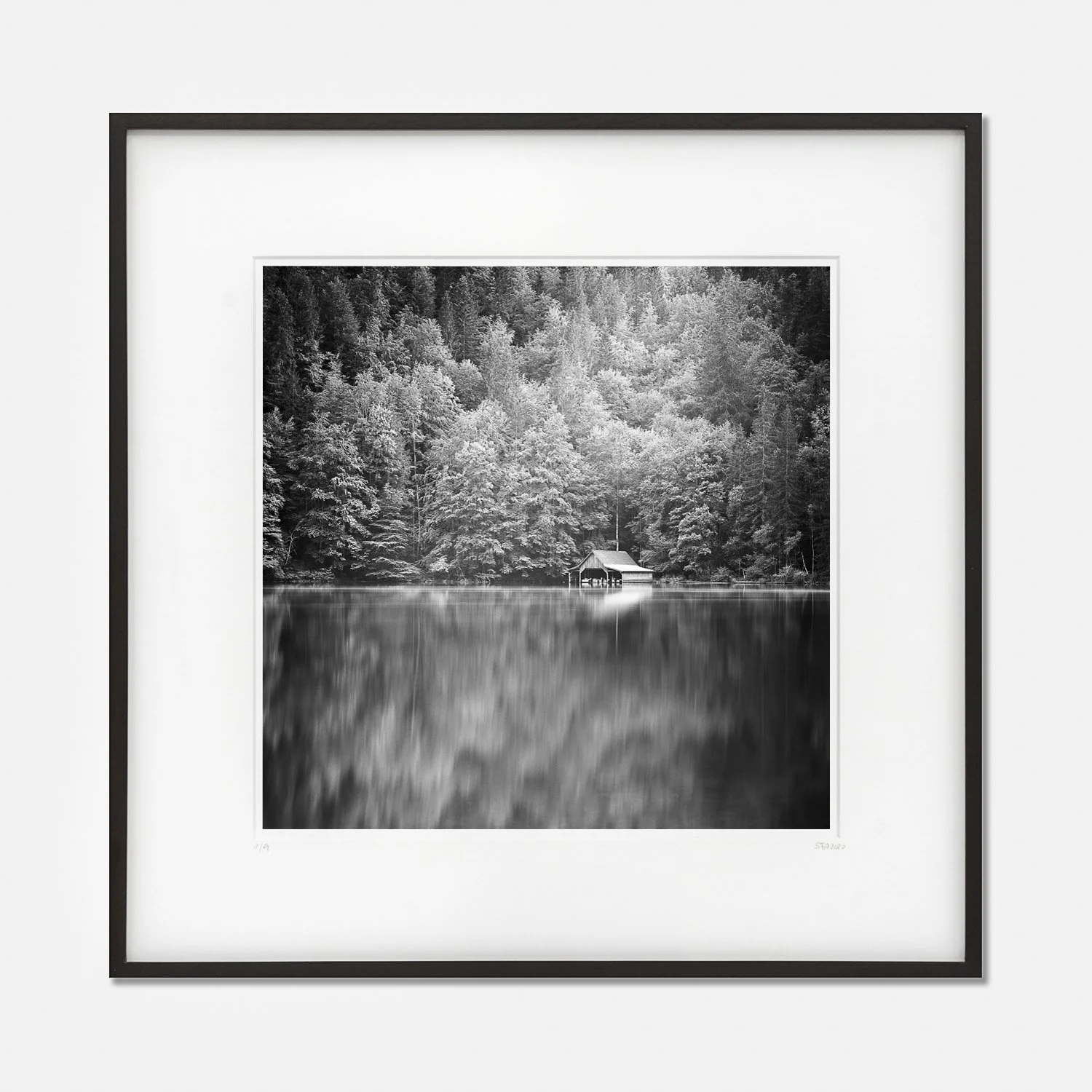 Framed black-and-white fine art photograph Boat House at Mountain Lake, Austria, by Gerald Berghammer, presented in a black wooden frame with a white archival mount.