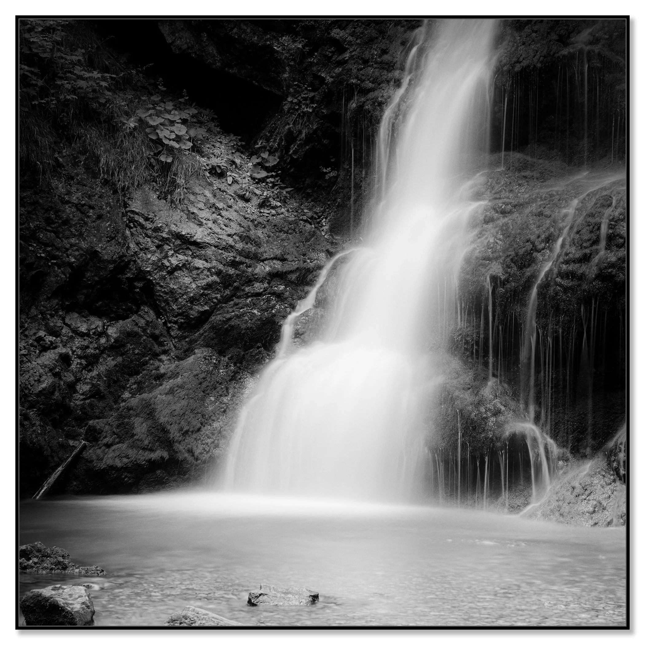 © 2020 Gerald Berghammer - Black and white long exposure abstract photography.  Waterfall descending into a calm pool surrounded by rocky terrain. Chromaluxe framed black