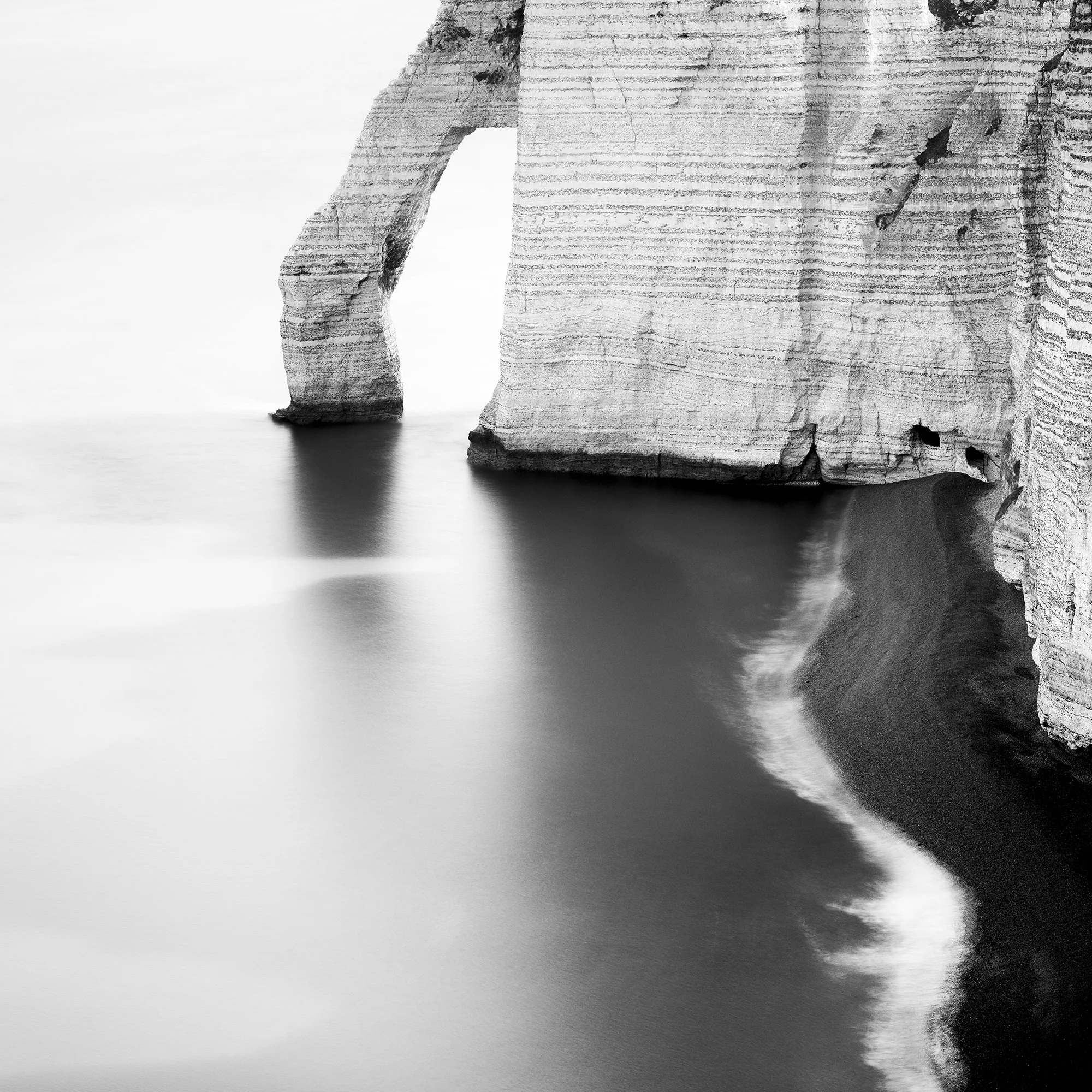 Detail of The Sea Arch at Étretat, France, with long-exposure water and limestone cliffs. Photo by Gerald Berghammer.