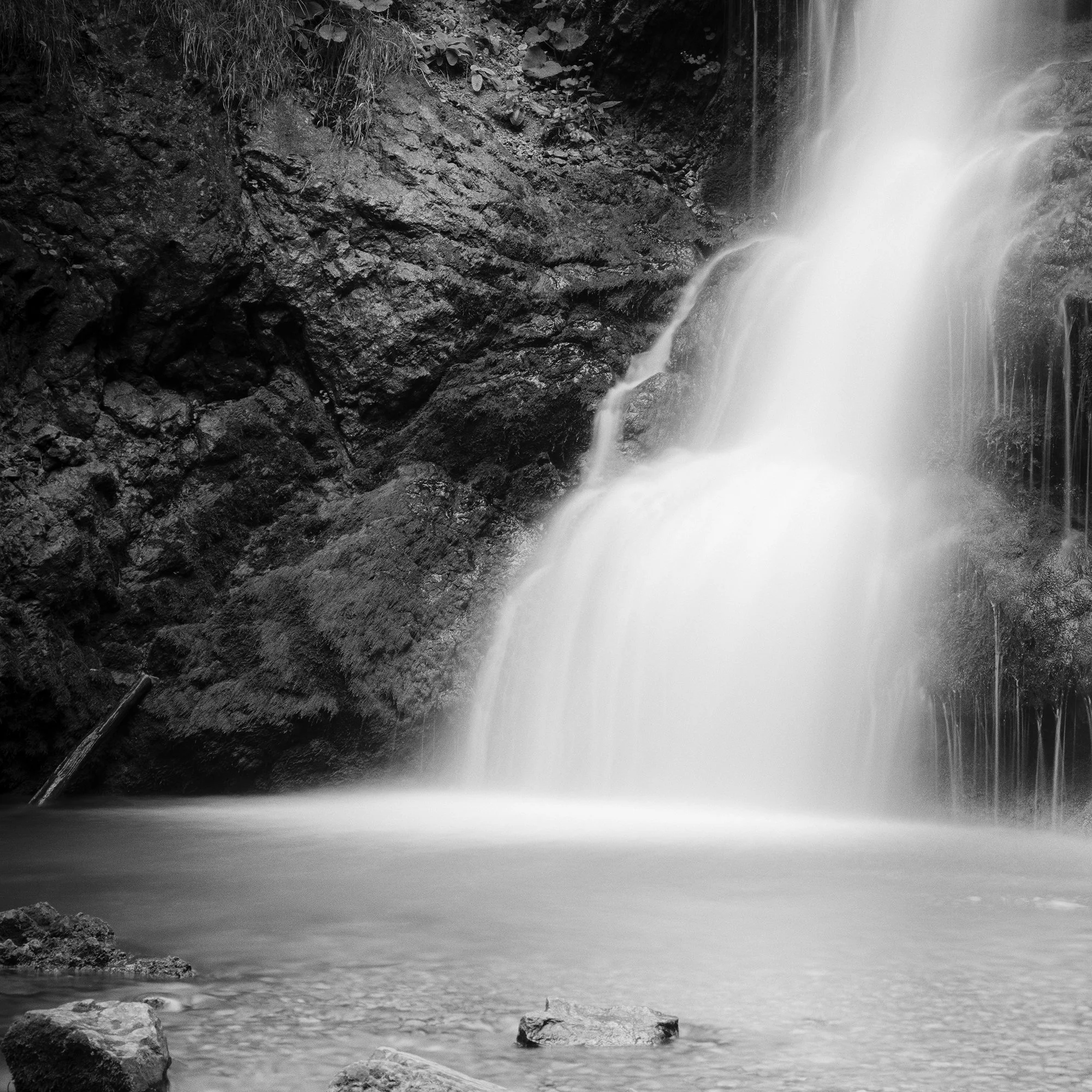 © 2020 Gerald Berghammer - Black and white long exposure abstract photography.  Waterfall descending into a calm pool surrounded by rocky terrain. Print detail 1