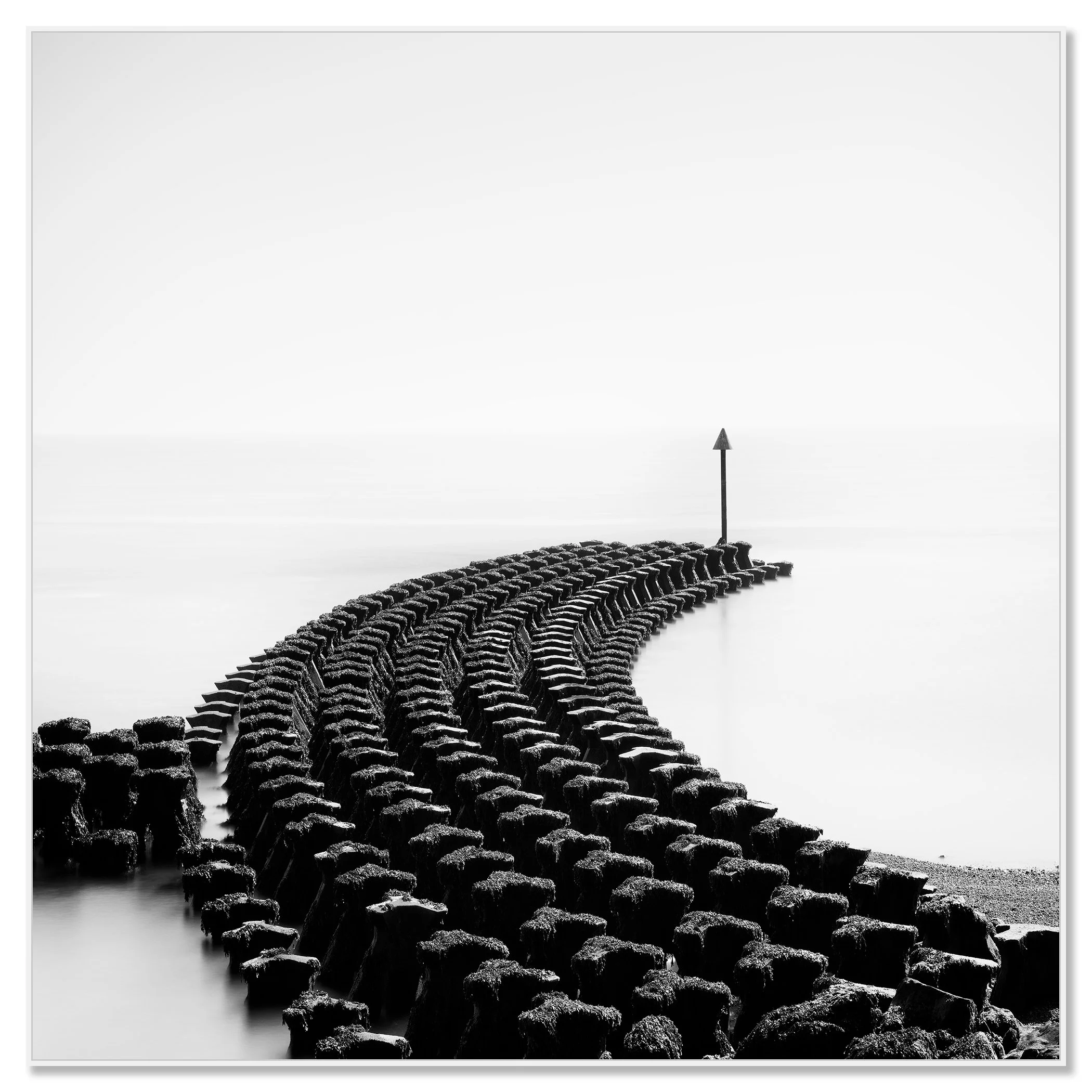 Black and white seascape with curved timber groynes leading to a coastal warning sign – framed ArtBox white