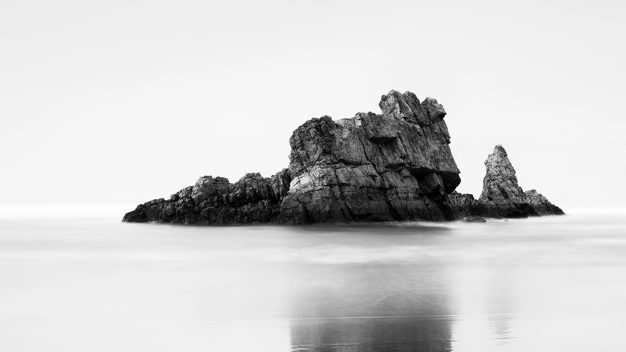 Rock on the Beach Panorama Study 1, panoramic black-and-white seascape with a reflected rock formation in the Bay of Biscay, Spain.