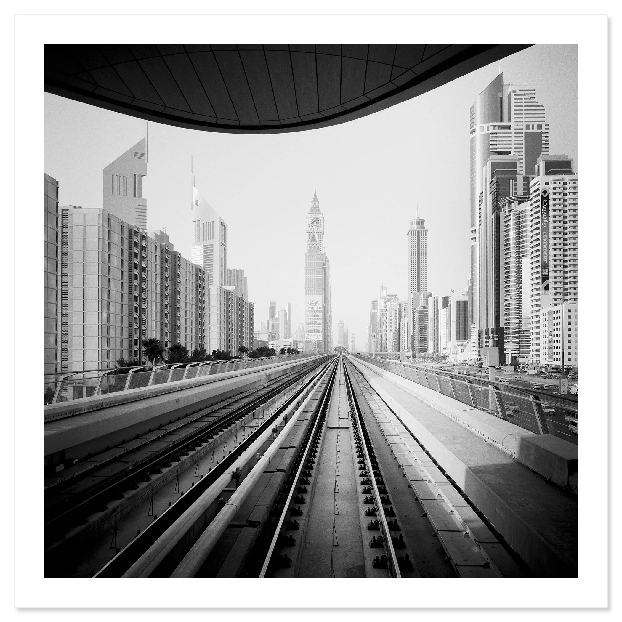 Gerald Berghammer - Black and white cityscape photo. City skyline viewed from a railway track, with modern skyscrapers and a clock tower in the distance. Fine art print only