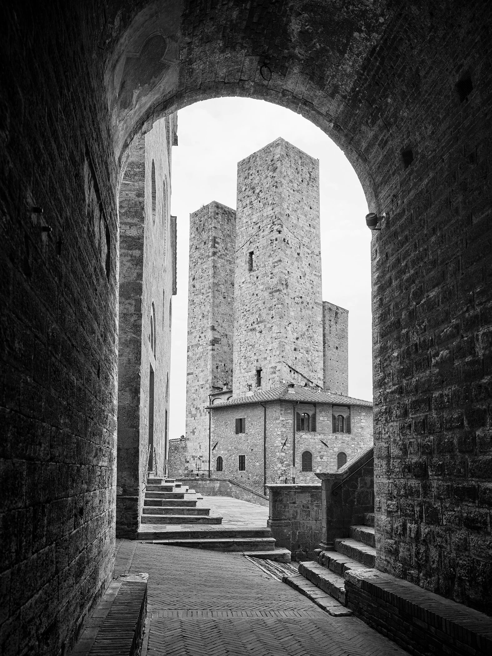 San Gimignano Study 1, black-and-white fine art photograph of medieval towers framed by a stone archway in Tuscany, Italy, by Gerald Berghammer.