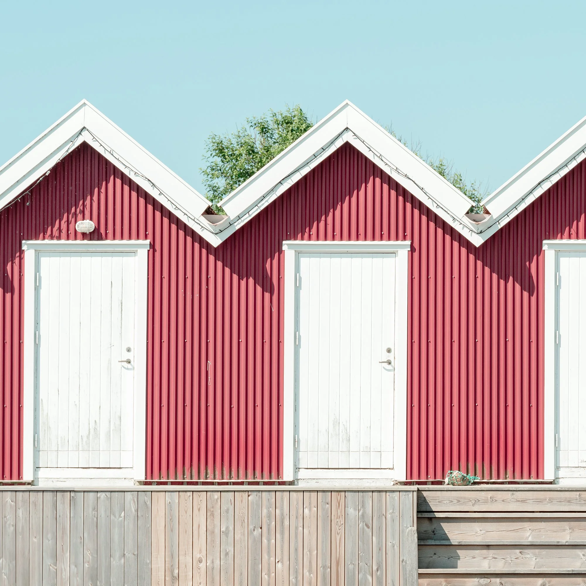 Cropped detail of Red Beach Huts Study 1 showing the geometric rhythm of red wooden beach huts in Sweden.