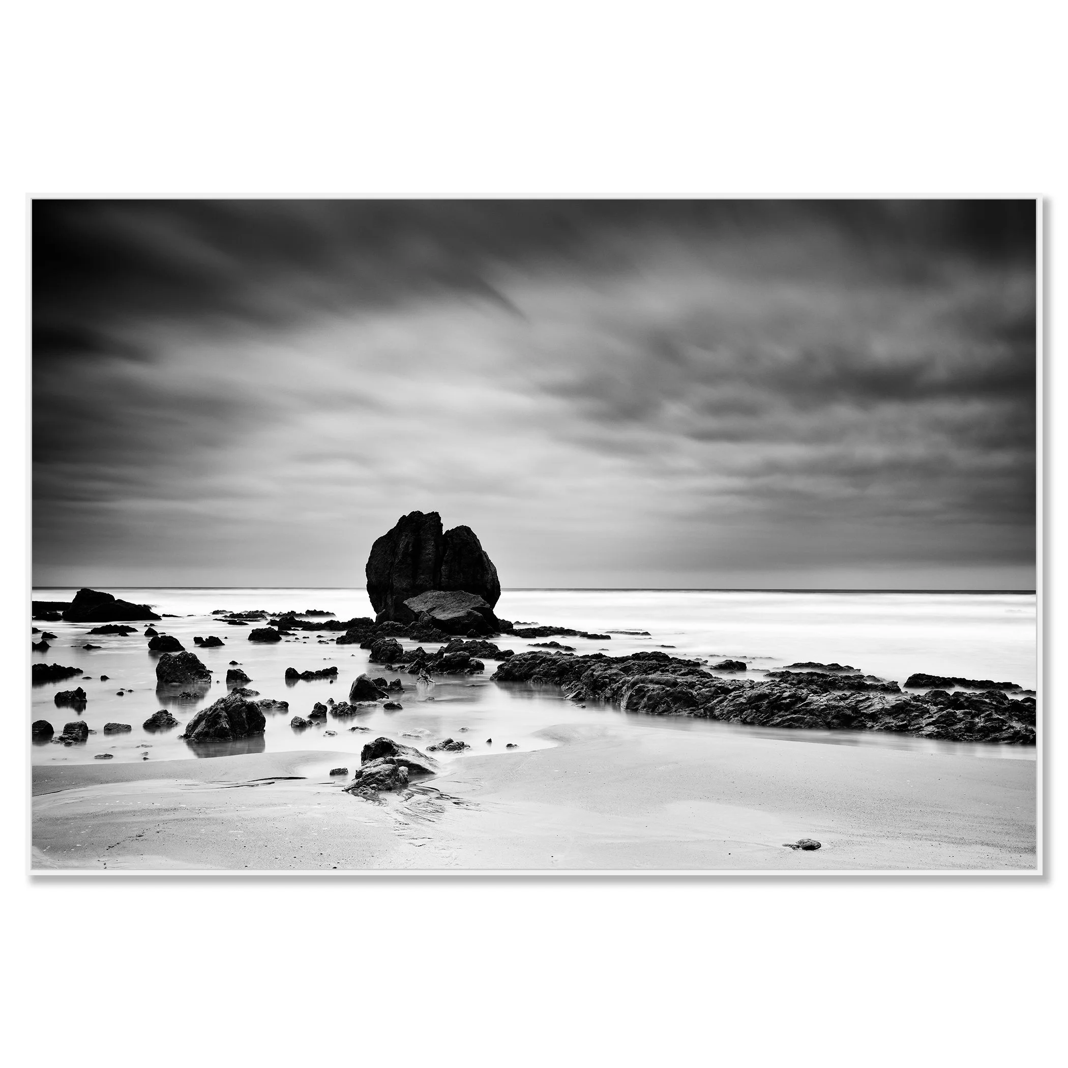 Long-exposure monochrome photo of a rocky beach, soft waves and overcast sky creating a moody seascape – framed ArtBox white