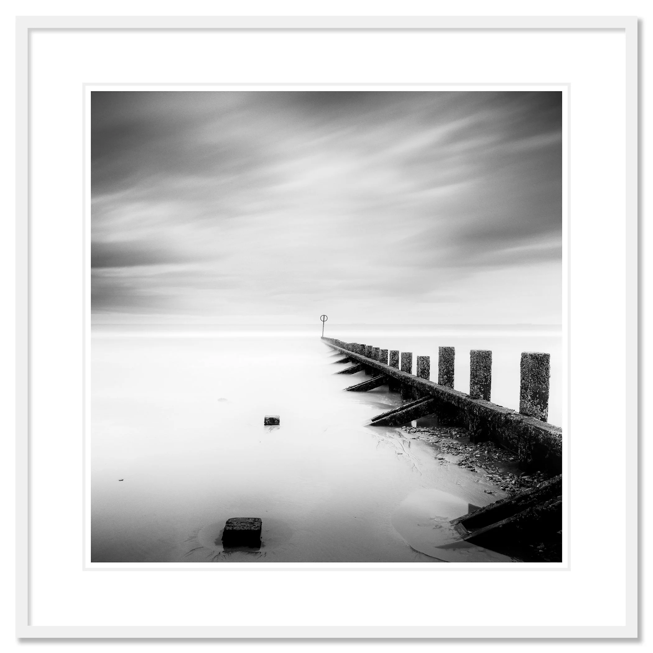 © 2012 Gerald Berghammer - Black and white landscape photography. A wooden wave breaker extending into a calm body of water, with a circular marker at the end. Classic framed white