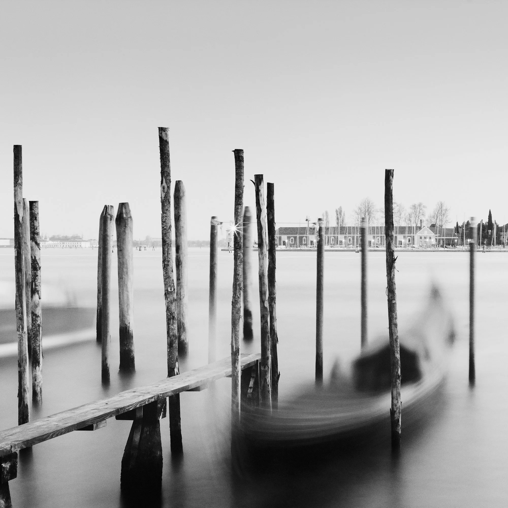 Detail of Basilica di San Giorgio Maggiore Panorama by Gerald Berghammer showing blurred gondolas and wooden mooring posts in Venice.