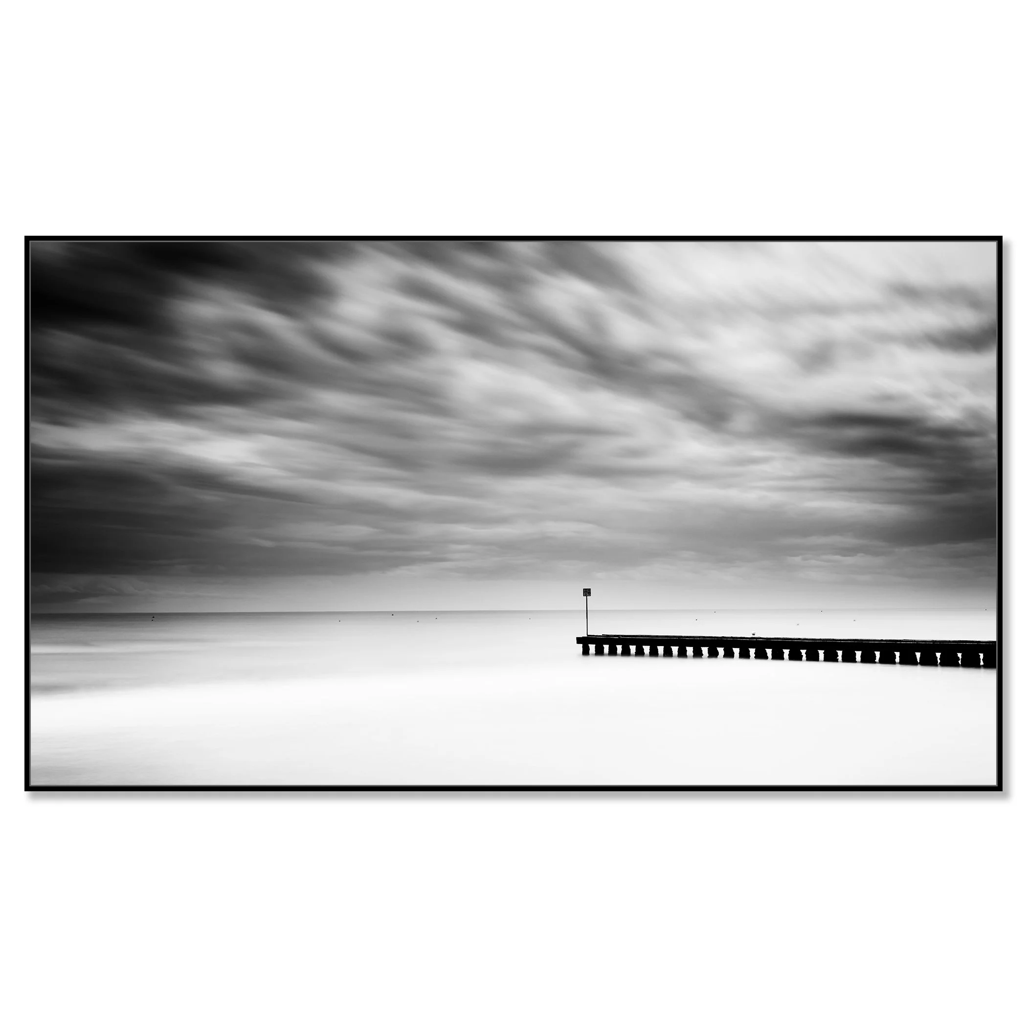A wooden pier extending into a calm body of water with a cloudy sky and stormy weather – framed ArtBox black