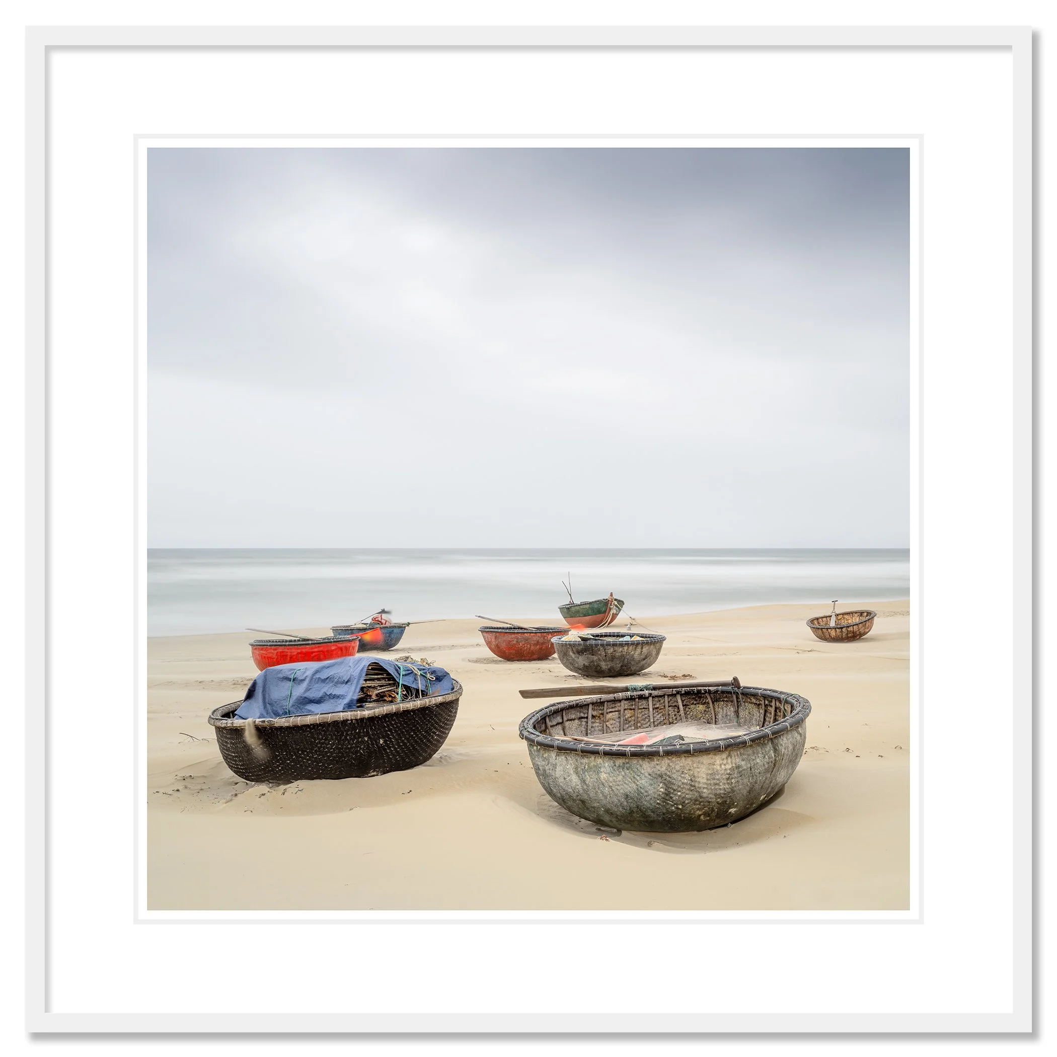 Gerald Berghammer - Color landscape photography. Several small boats resting on a sandy beach with calm ocean water under an overcast sky. Classic framed white