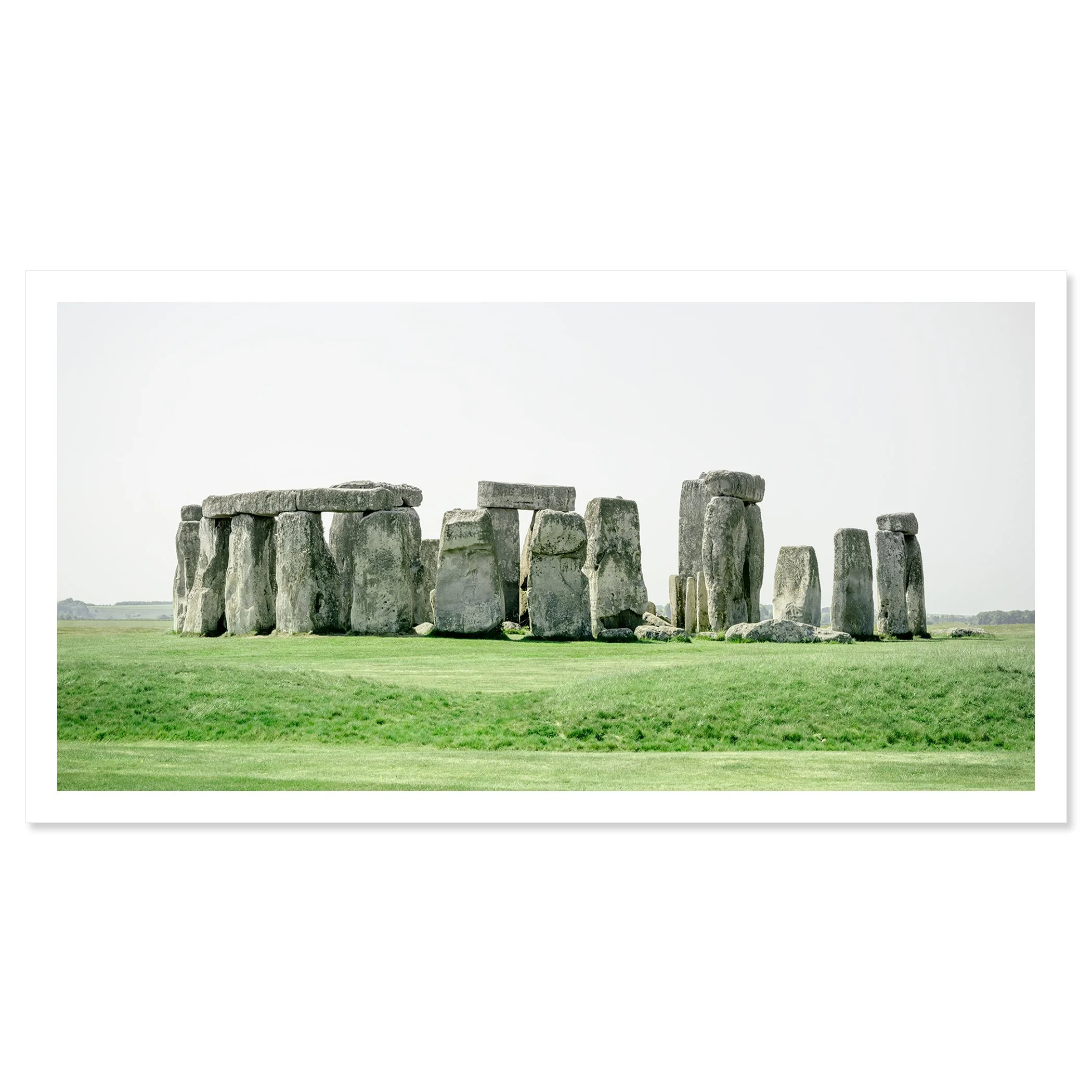 Gerald Berghammer - Color landscape panorama photography. Historic Stonehenge monument with large standing stones on a grassy field under a gray sky. Fine art print only