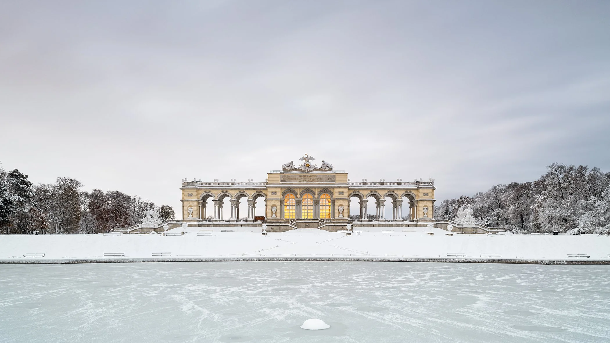 Snow-Covered Gloriette displayed in a modern interior, mounted on aluminium Dibond in a black ArtBox frame by Gerald Berghammer.