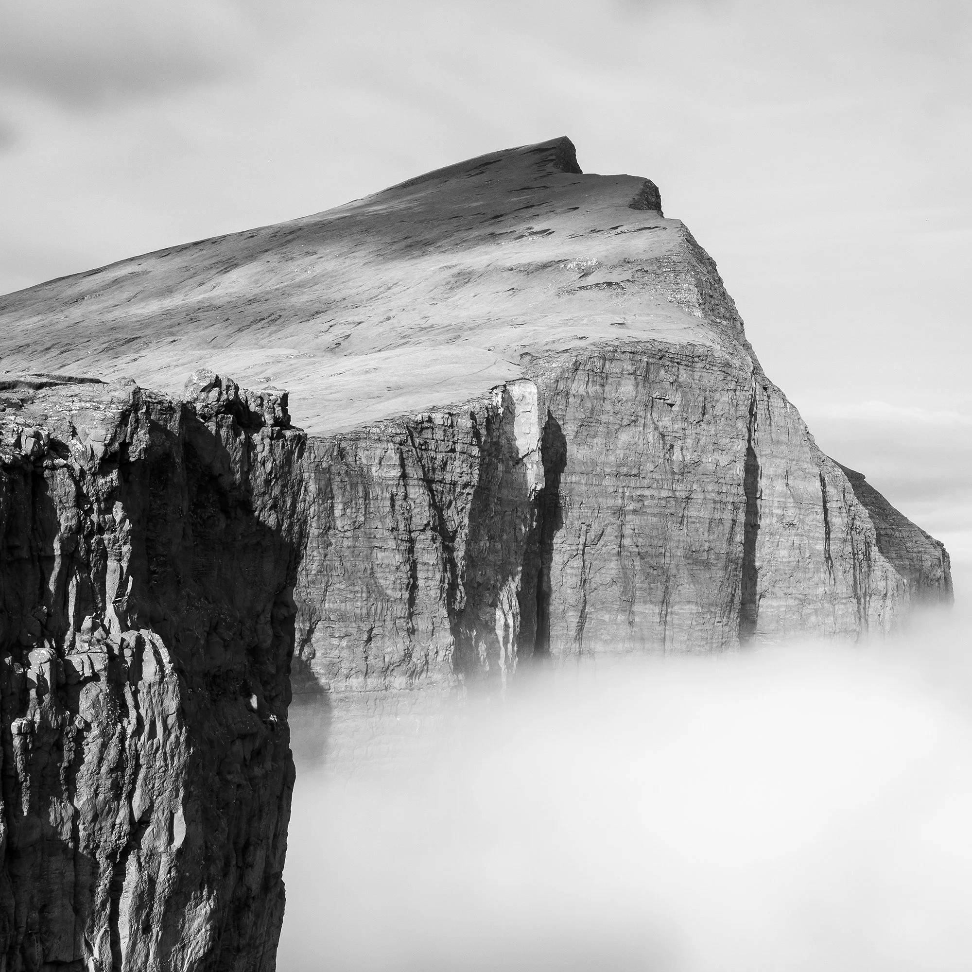Close-up of Trælanípa’s layered basalt cliff face and summit above mist in the Faroe Islands, by Gerald Berghammer.