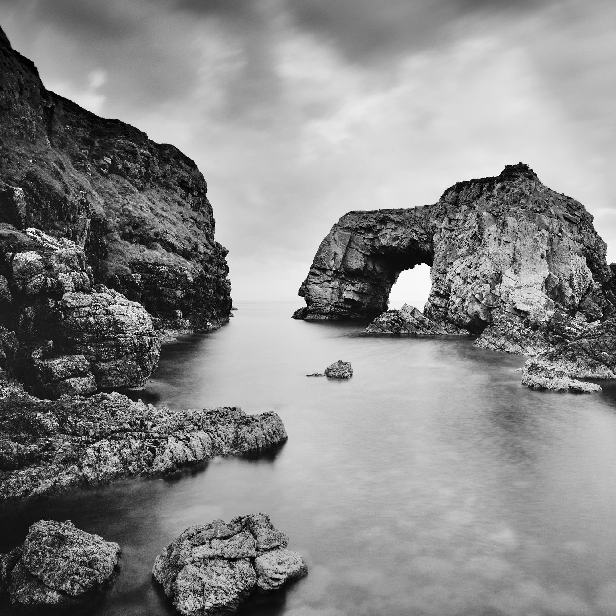 Detail of Great Pollet Sea Arch Study 3 showing rugged coastal cliffs, the sea arch and smooth long-exposure water in Ireland by Gerald Berghammer.