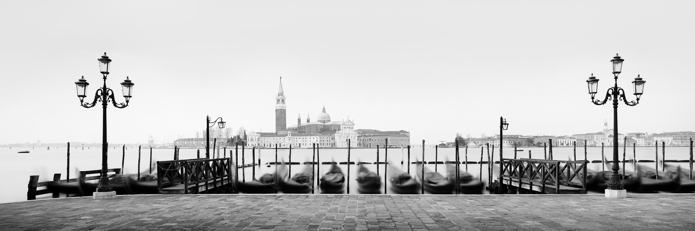 Black and white photograph of Venice with gondolas along the waterfront and San Giorgio Maggiore in the distance