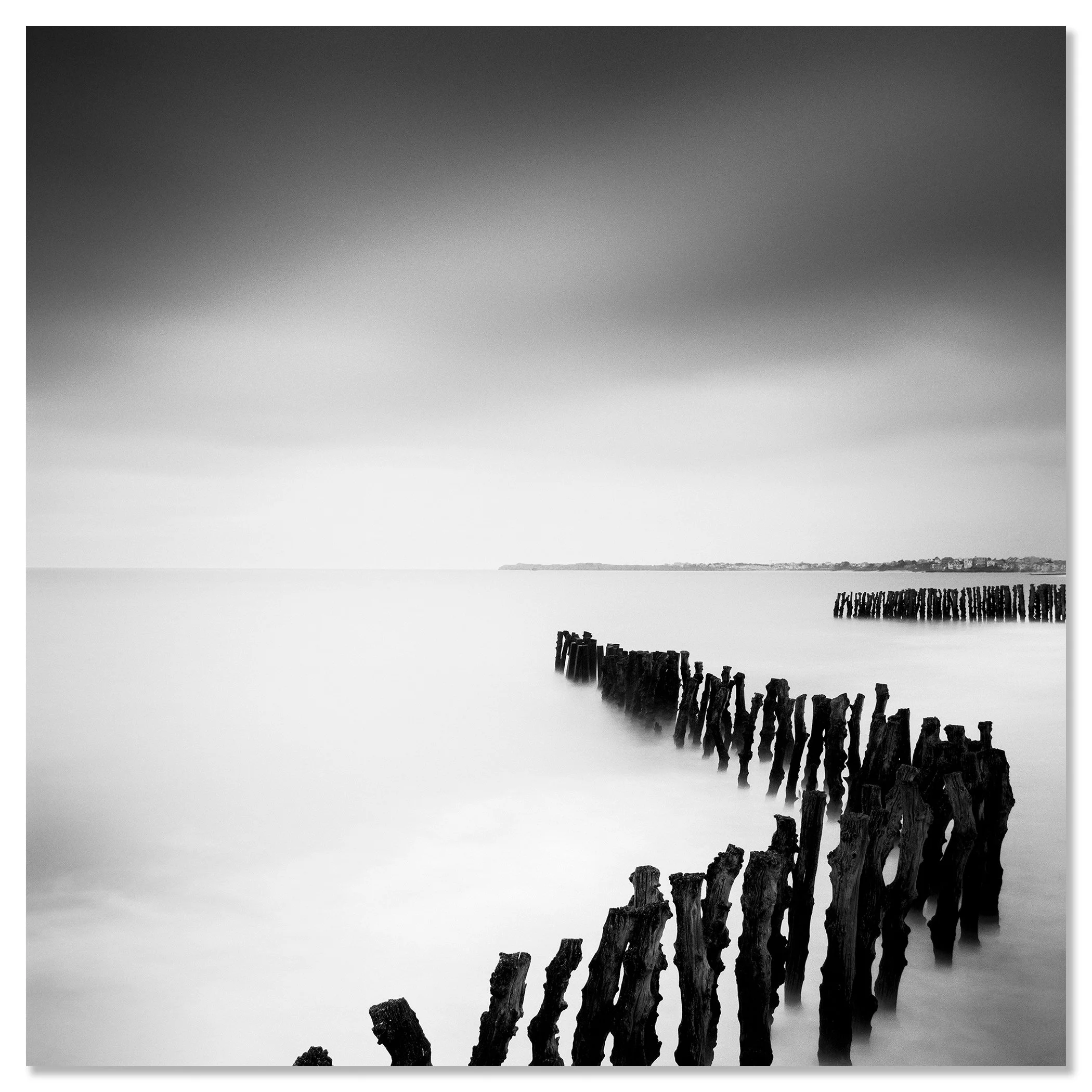 Monochrome long exposure seascape with wooden groynes, soft sea and distant shoreline – dibond frameless
