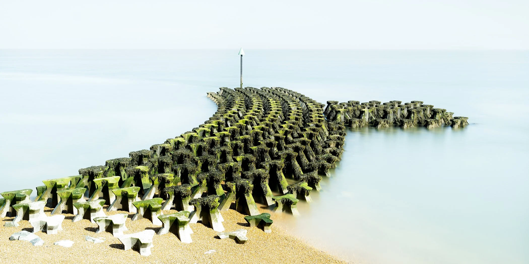 Cobbold’s Point, Colour Study 1 by Gerald Berghammer, minimalist colour photograph of moss-covered coastal structures extending into calm water in England.
