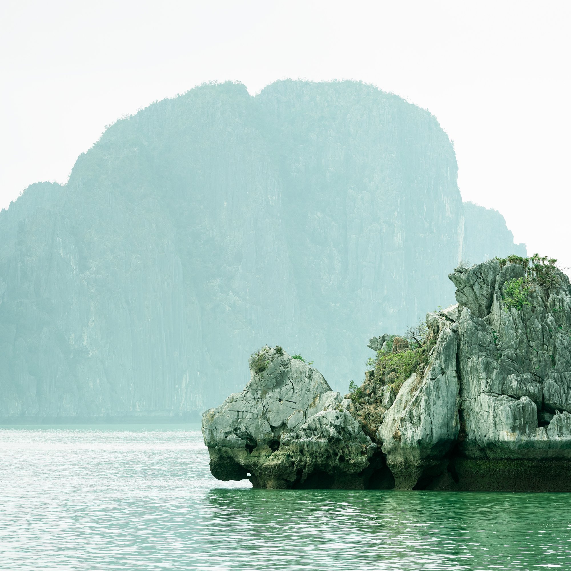 Gerald Berghammer - Color seascape photography. Large rocks rising from the water with, surrounded by calm water and distant limestone cliffs and islands. Print detail 1