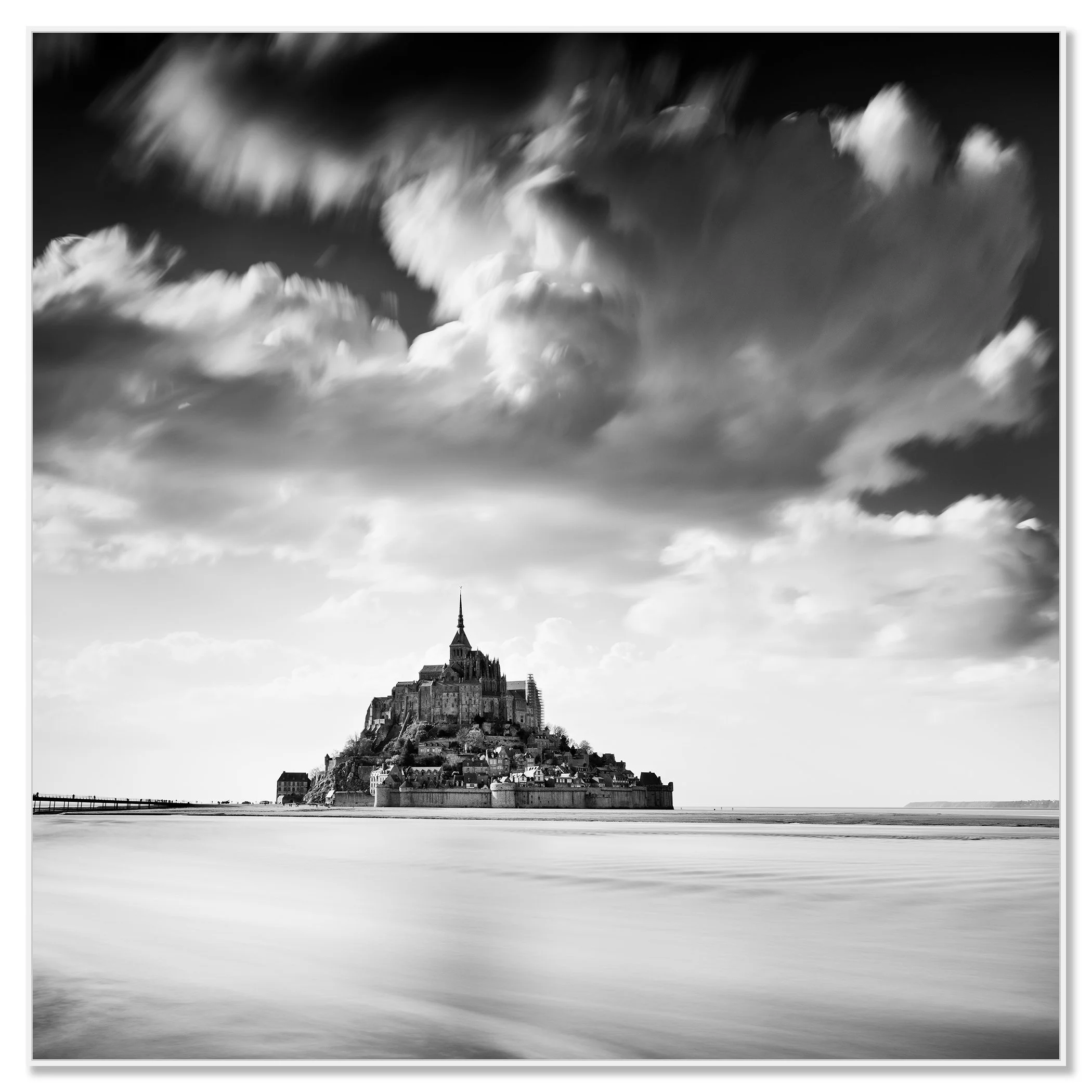Black and white photograph of Mont Saint-Michel rising from calm tidal waters beneath dramatic clouds – framed ArtBox white