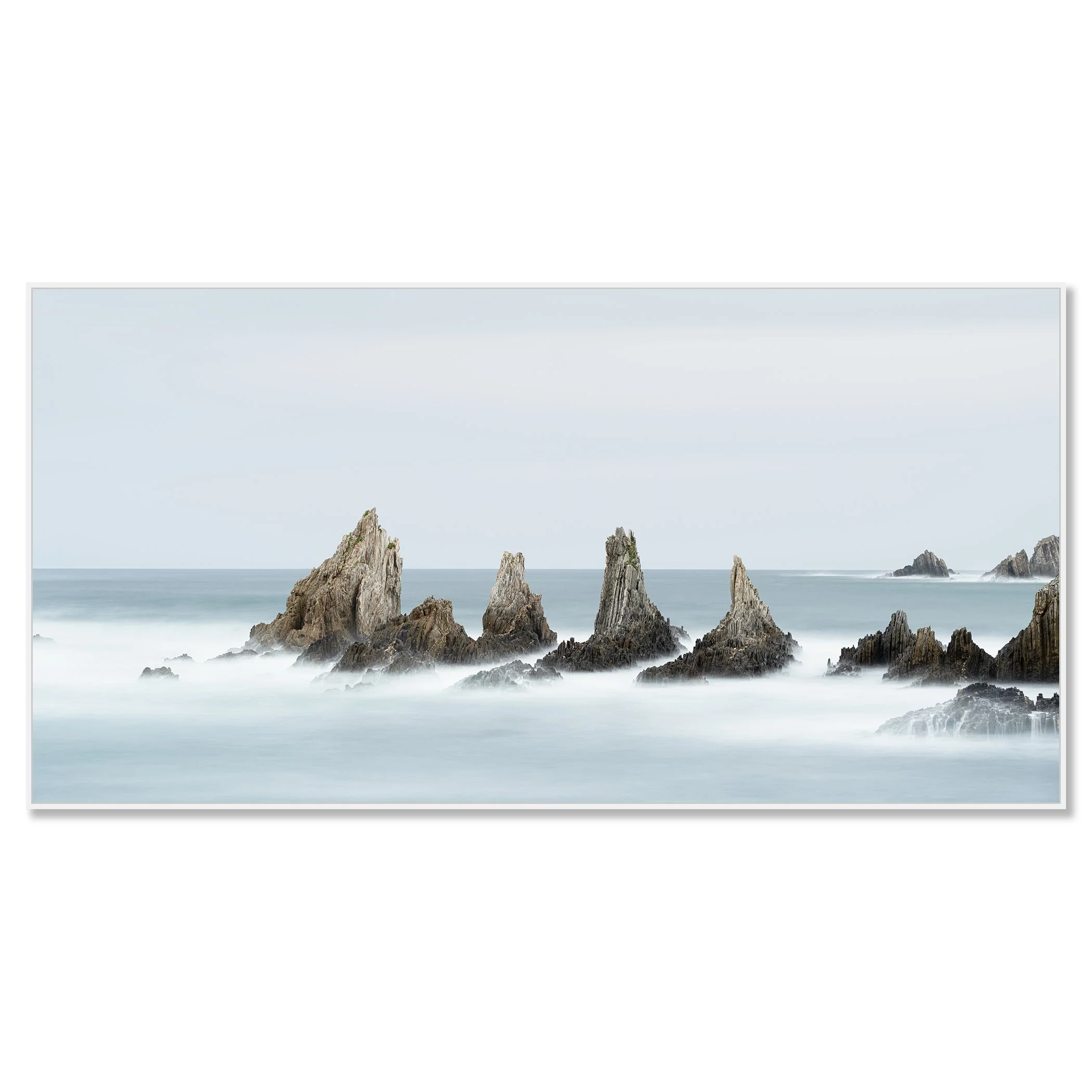 Long exposure minimalist seascape photo of jagged ocean rocks with misty water and cloudy sky – framed ArtBox white