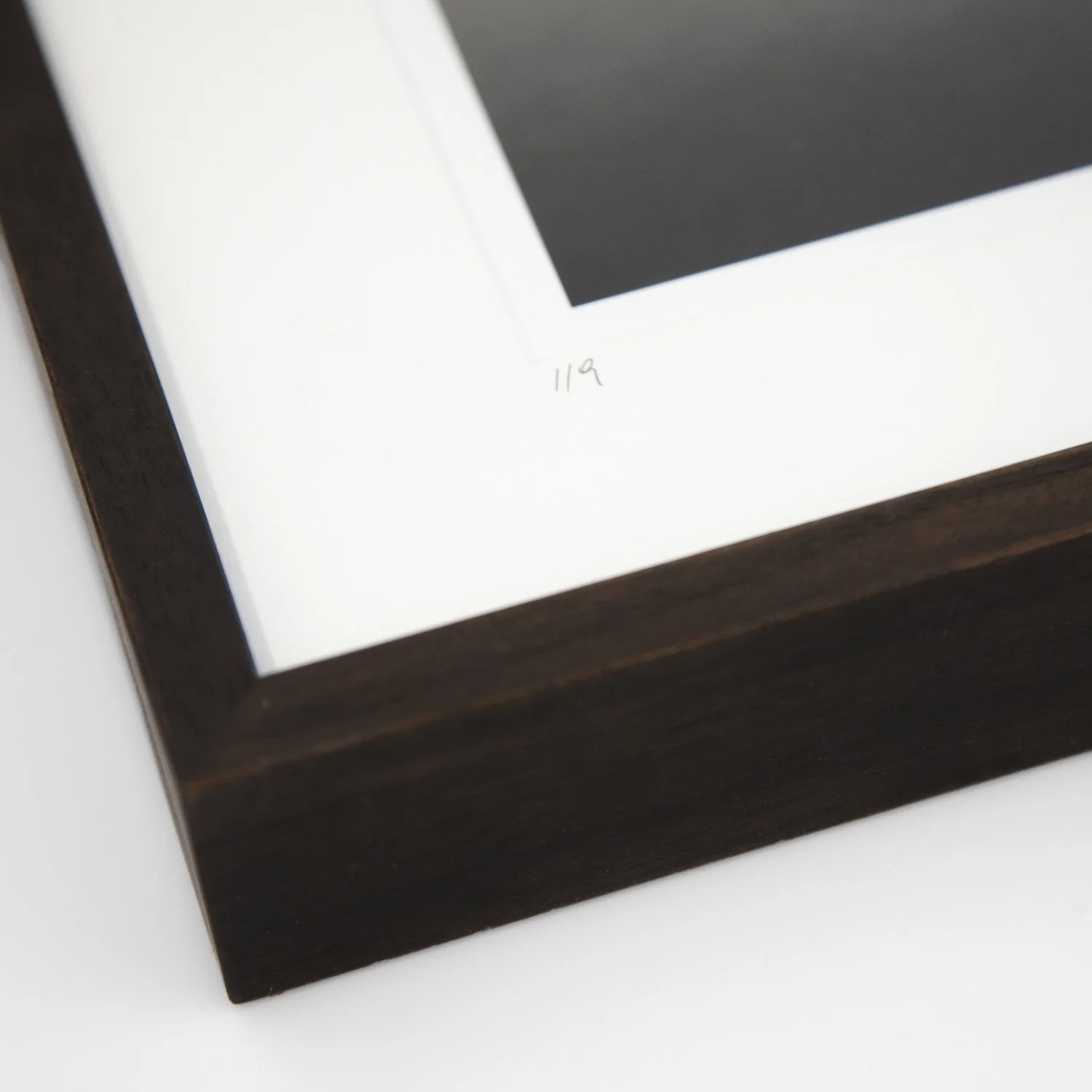 Close-up of the handwritten edition number 1/9, natural-white archival mount and dark-brown wooden frame, Phragmites Study 1 by Gerald Berghammer.