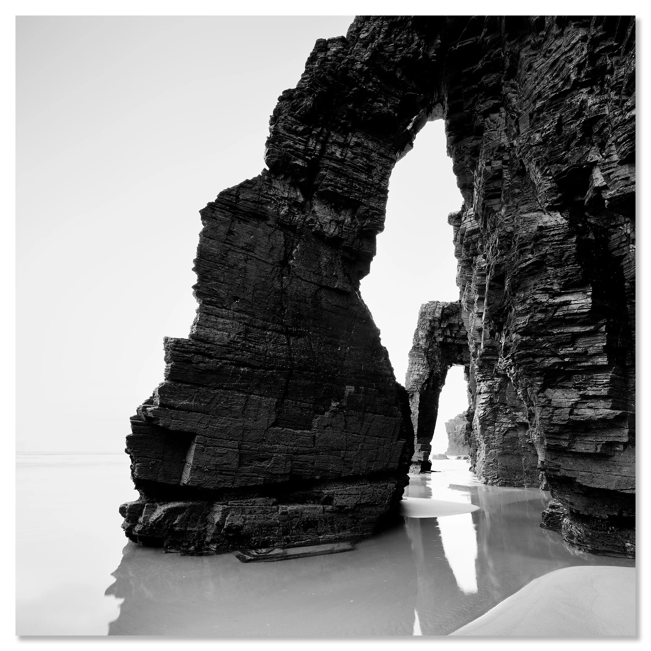 Arches on Catedrais Beach Study 4 shown as a frameless black-and-white aluminium Dibond print by Gerald Berghammer.