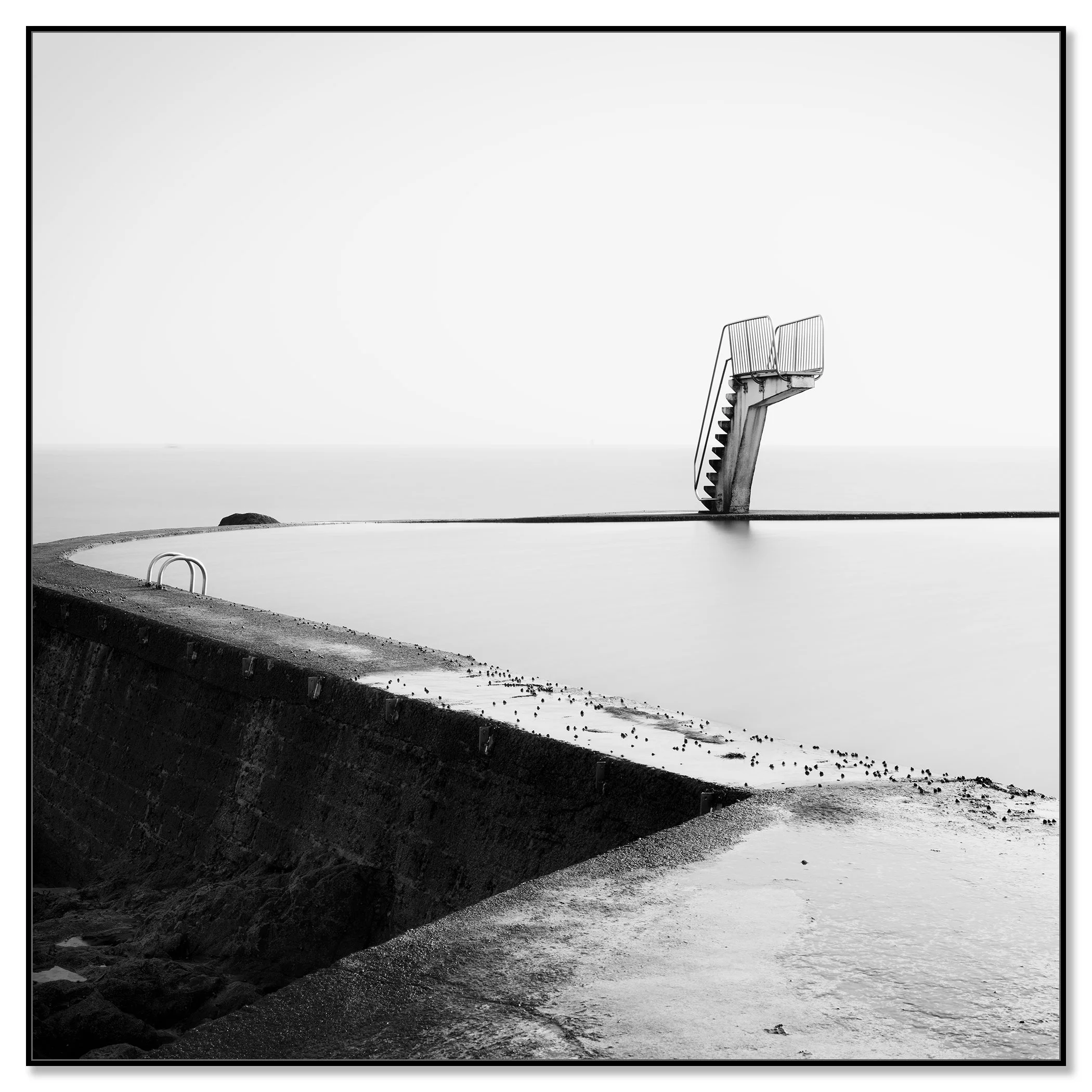 Empty diving platform in a quiet seawater pool on the coast, captured in black and white – framed ArtBox black