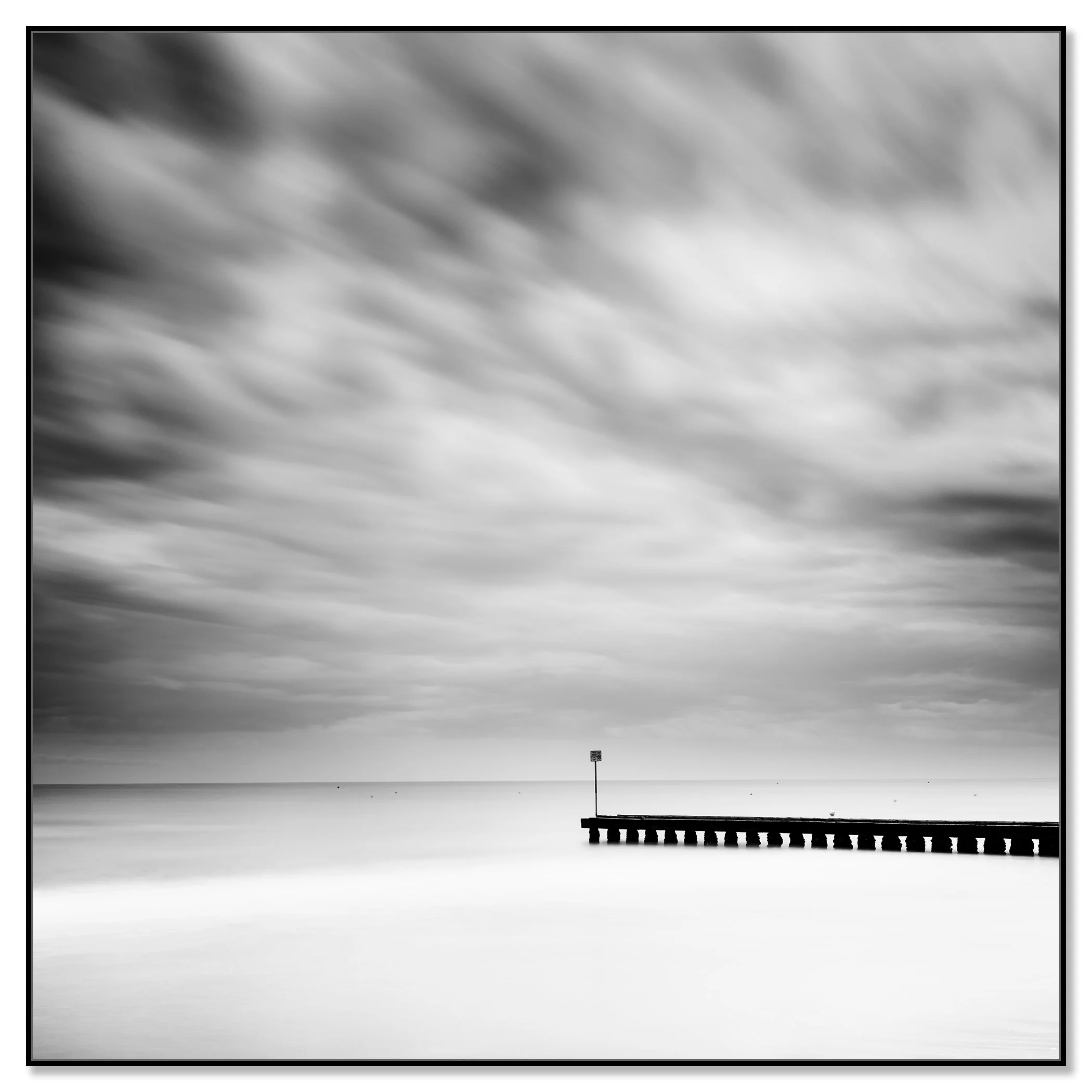 Wooden Pier in the Sea Study 1 – black-and-white long-exposure seascape from Italy mounted on aluminium Dibond in a black ArtBox frame by Gerald Berghammer.