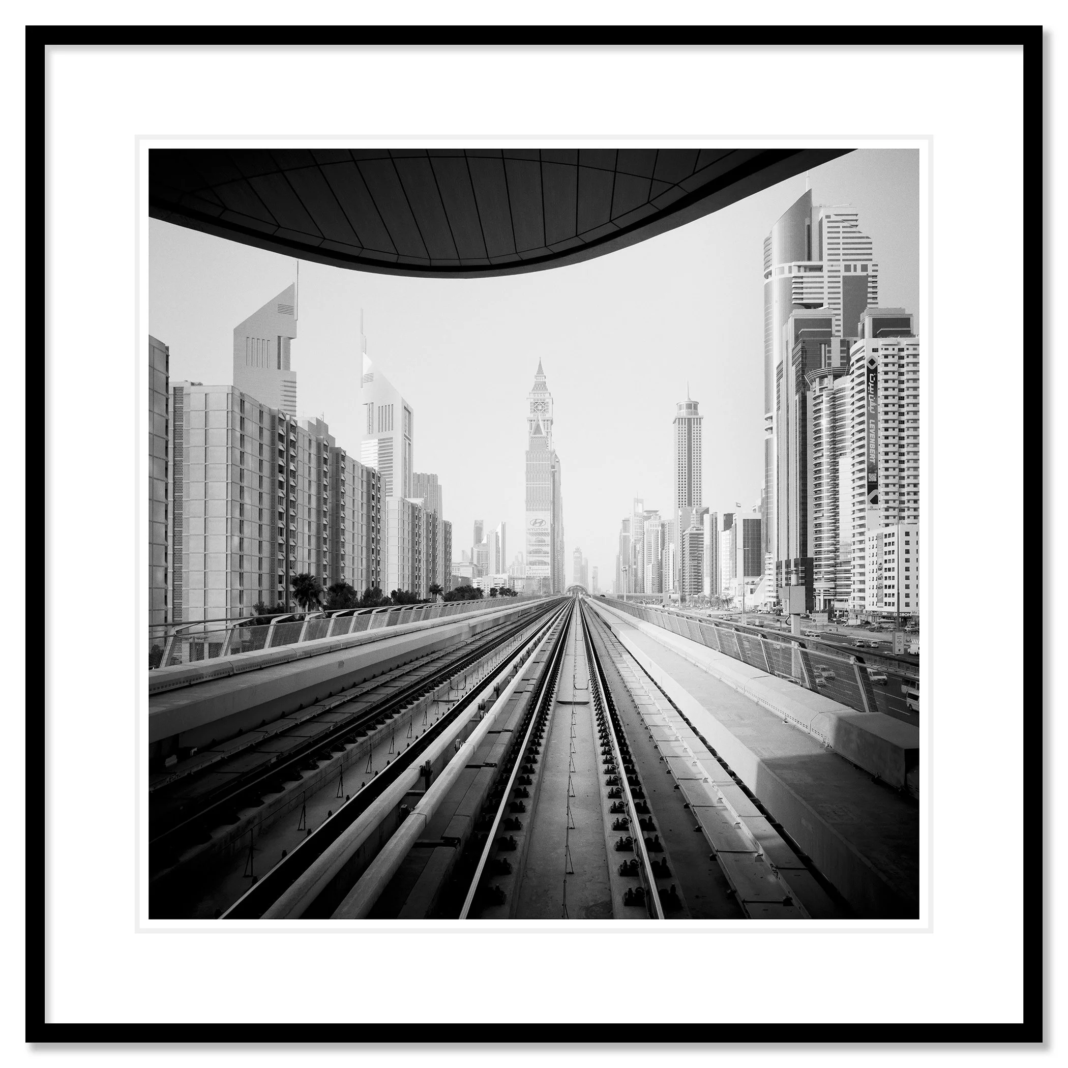 Gerald Berghammer - Black and white cityscape photo. City skyline viewed from a railway track, with modern skyscrapers and a clock tower in the distance. Classic framed black