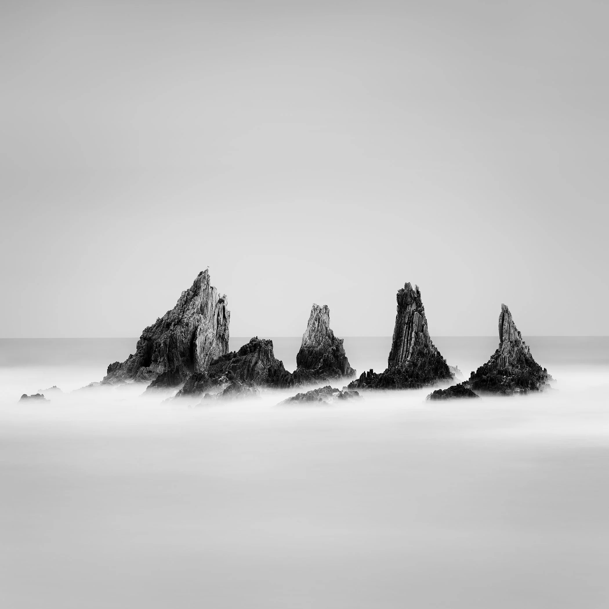 Rocky Peaks Study 1 by Gerald Berghammer, minimalist black-and-white long-exposure seascape of five rugged sea stacks in the Atlantic Ocean, Spain.