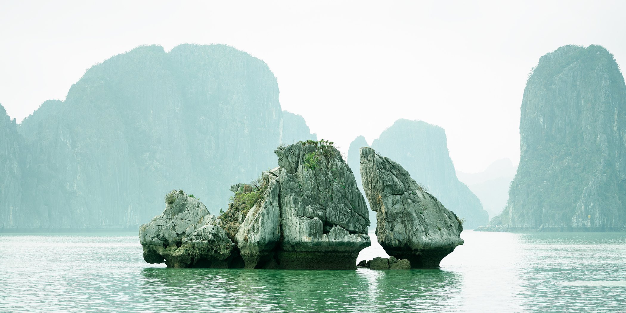 Panoramic view of sculptural limestone rock formations rising from the emerald waters of Ha Long Bay, Vietnam. Photo by Gerald Berghammer.
