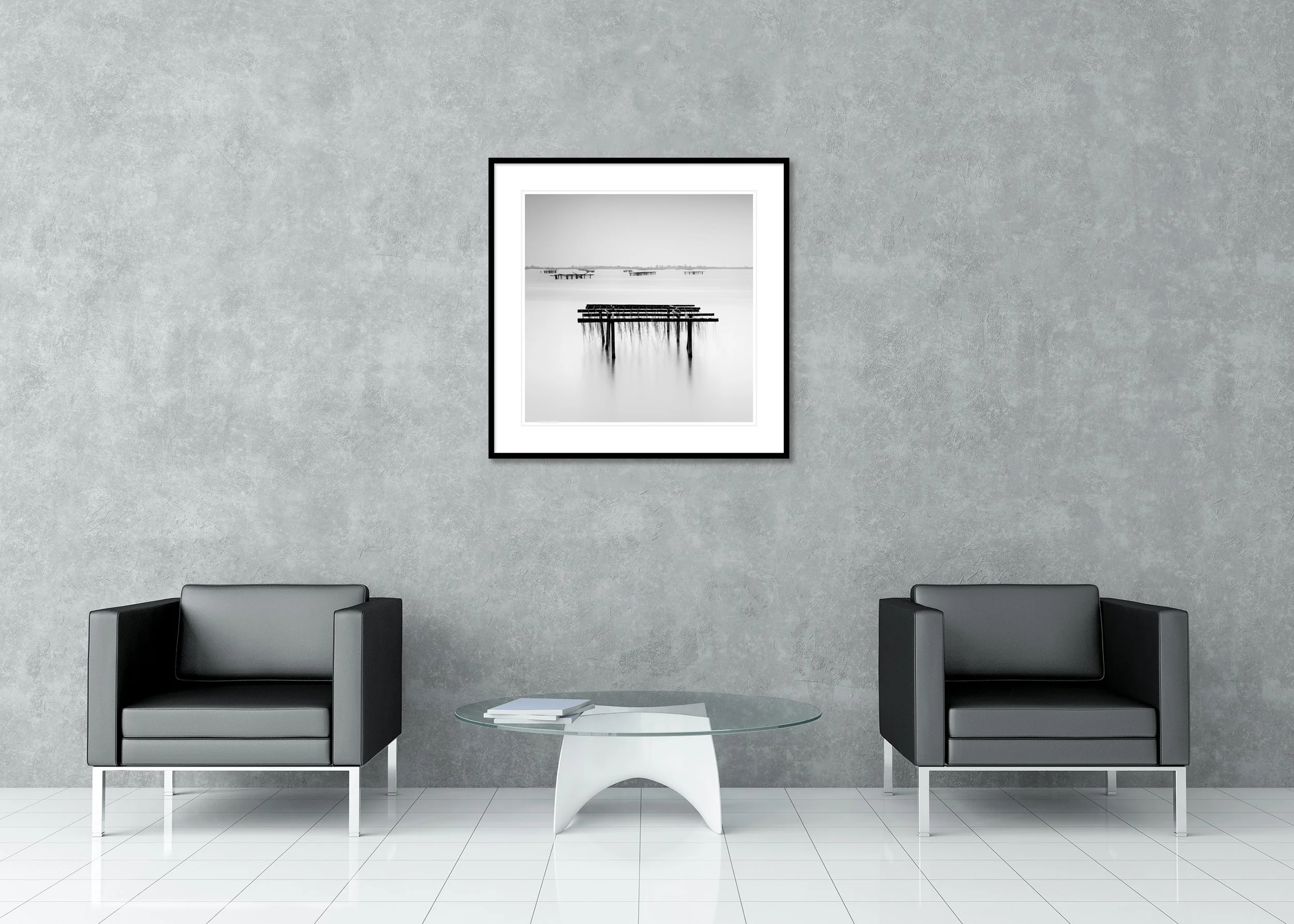 Long-exposure black-and-white coastal print with wooden fishing racks, smooth water and a distant shoreline, archival pigment print in a classic frame with a mount.