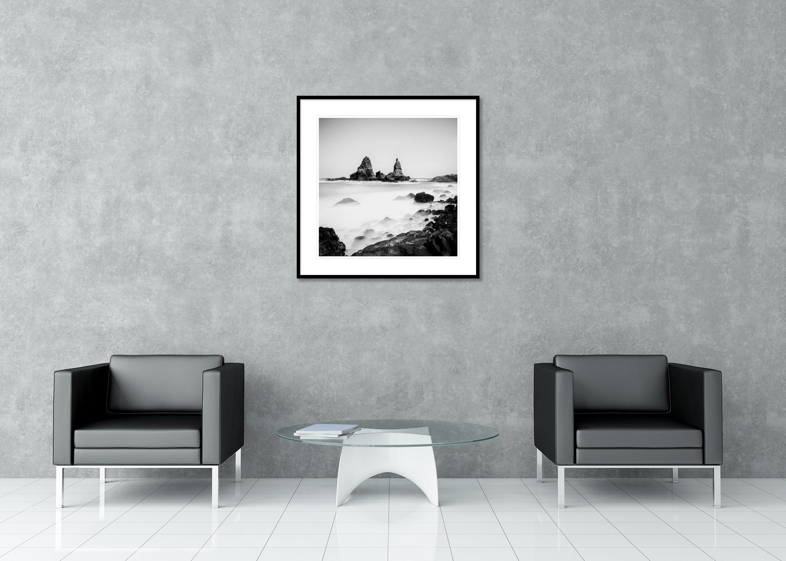 Black-and-white seascape with jagged sea stacks and misty surf over a rocky shore, archival pigment print in a classic frame with mount.