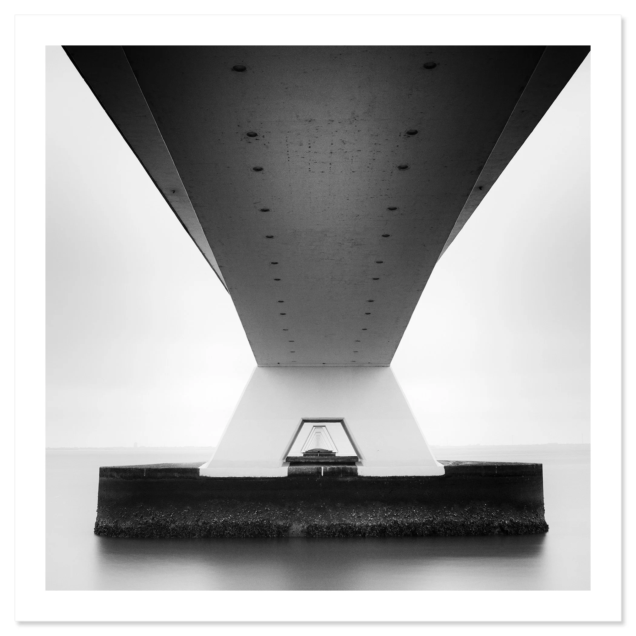 Gerald Berghammer - Black and white cityscape photo. Underneath view of a bridge with large support pillars, showing the underside and the water below. Fine art print only