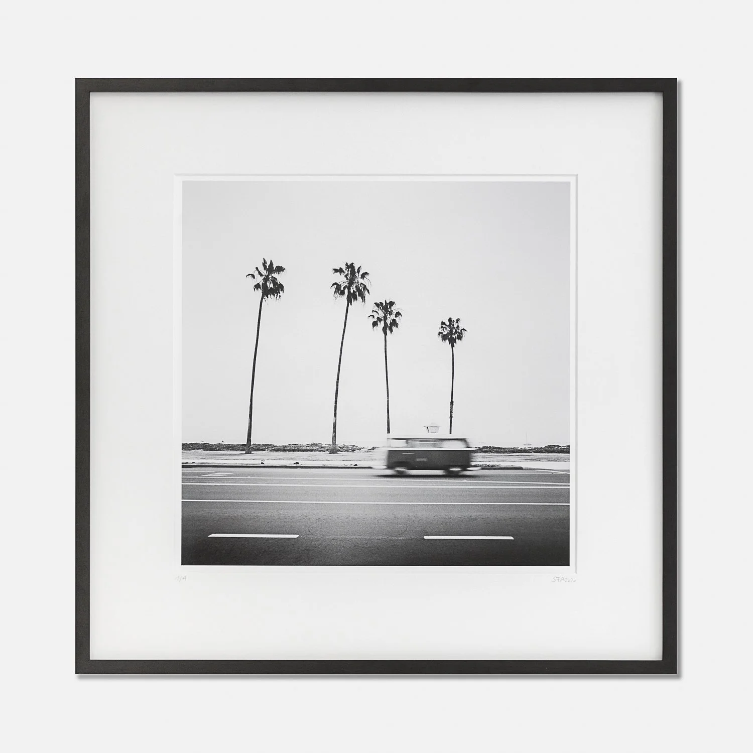 VW Bus T2, California, USA – framed black-and-white photograph of a moving camper van and palm trees by Gerald Berghammer.