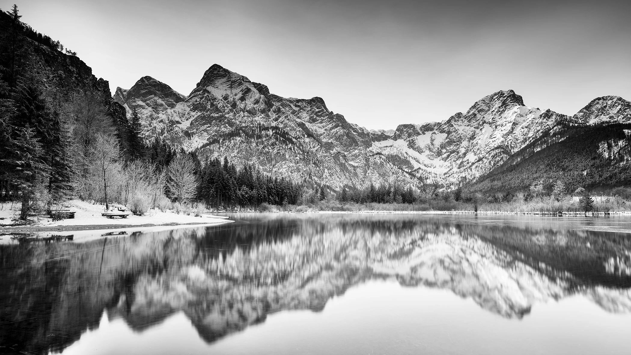 Monochrome waterscape at Almsee, Austria—lakeside winter panorama with mountains and reflections.