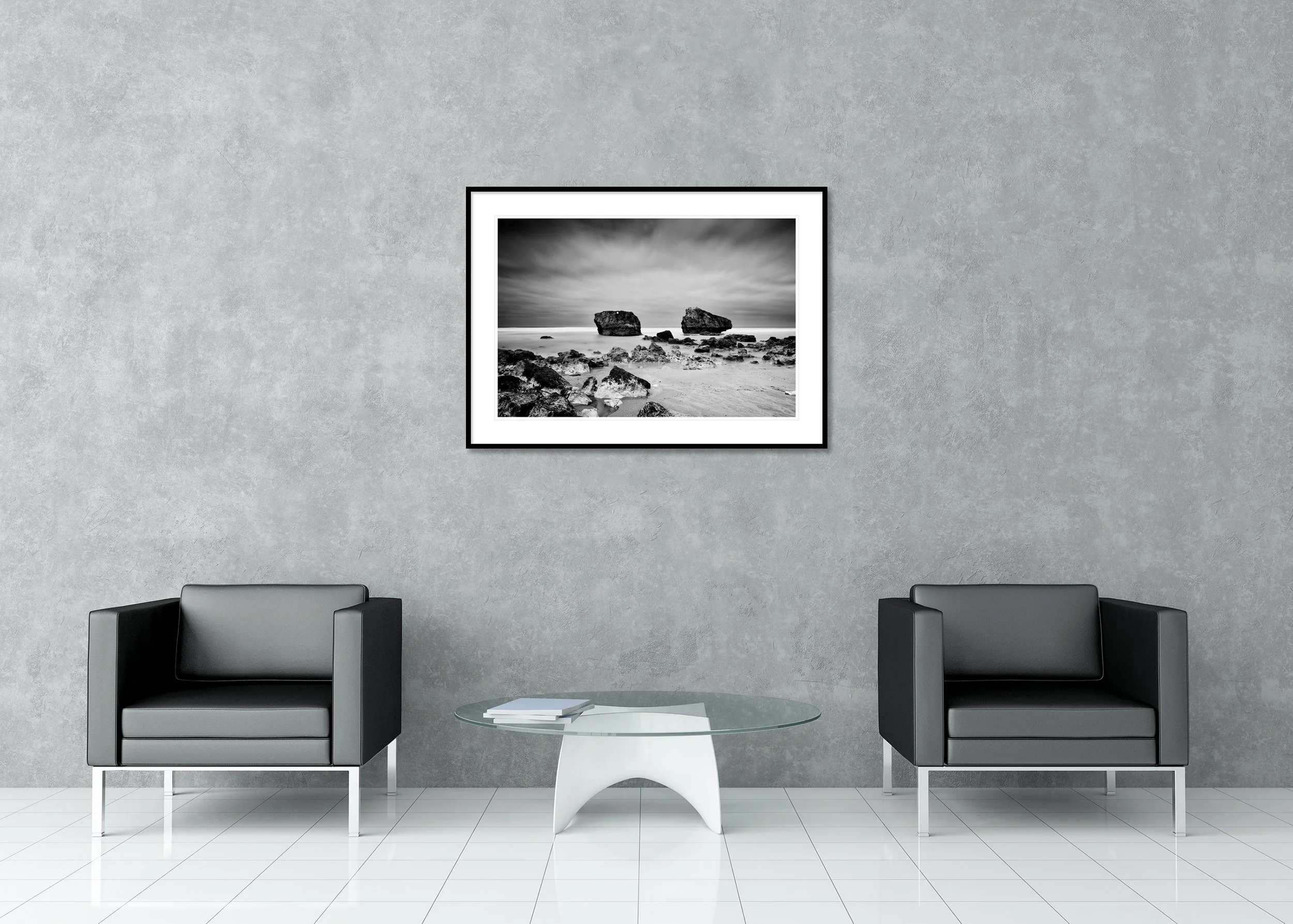 Black and white beach photograph with two rocks rising from the ocean under a cloudy sky, archival pigment print in a classic frame with mount