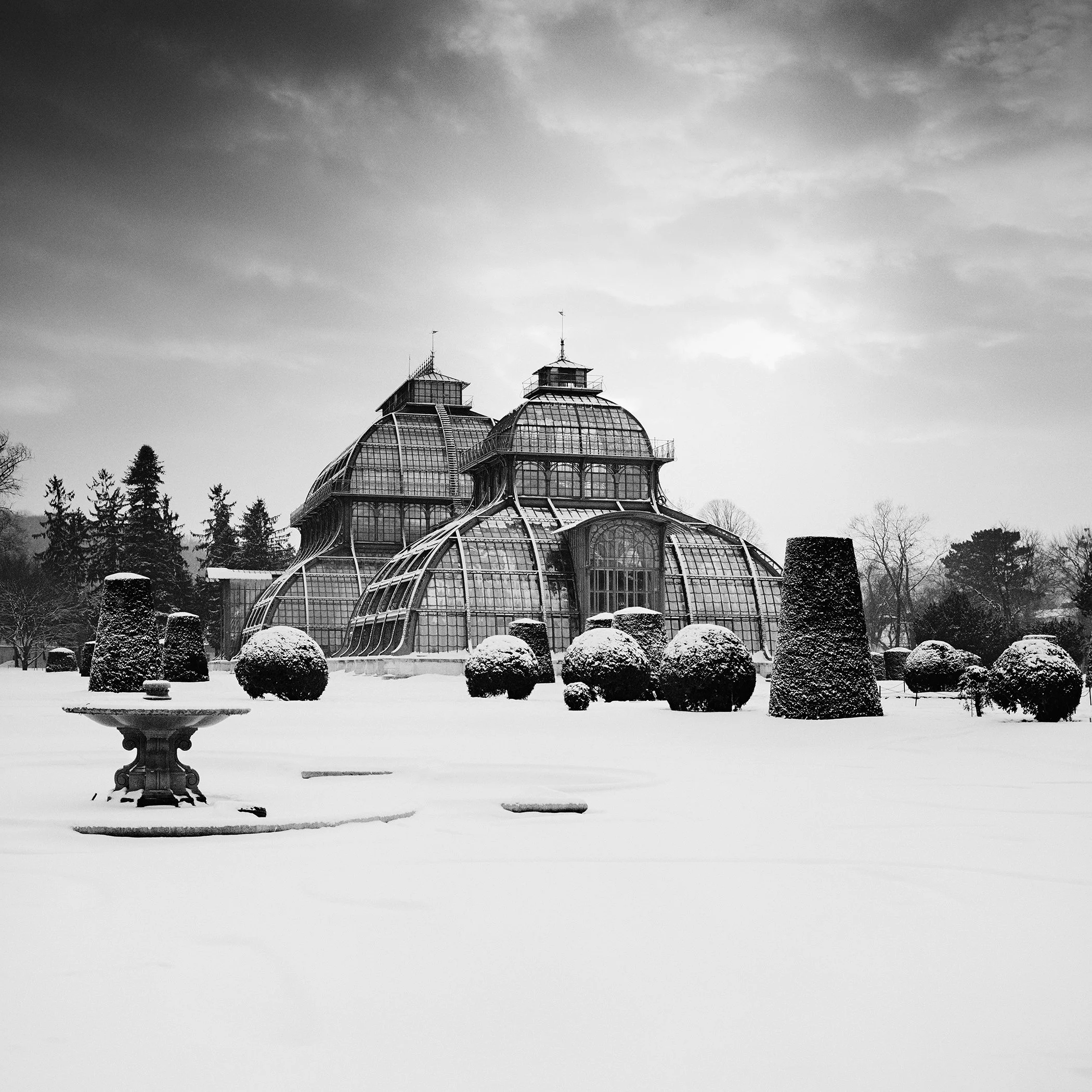 Black and white photo of the Palm House at Schönbrunn Palace, Vienna, in winter snow.
