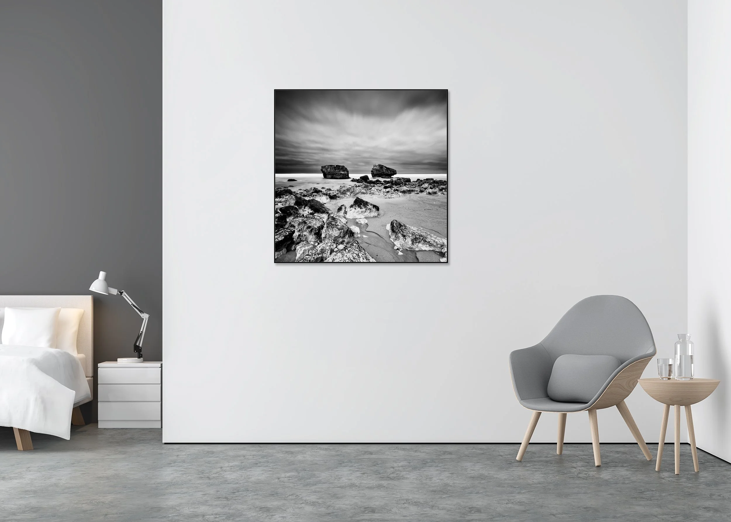 Monochrome seascape with stones on sand, two offshore rocks, and a moody sky, shown as a ChromaLuxe metal print in an aluminium ArtBox.