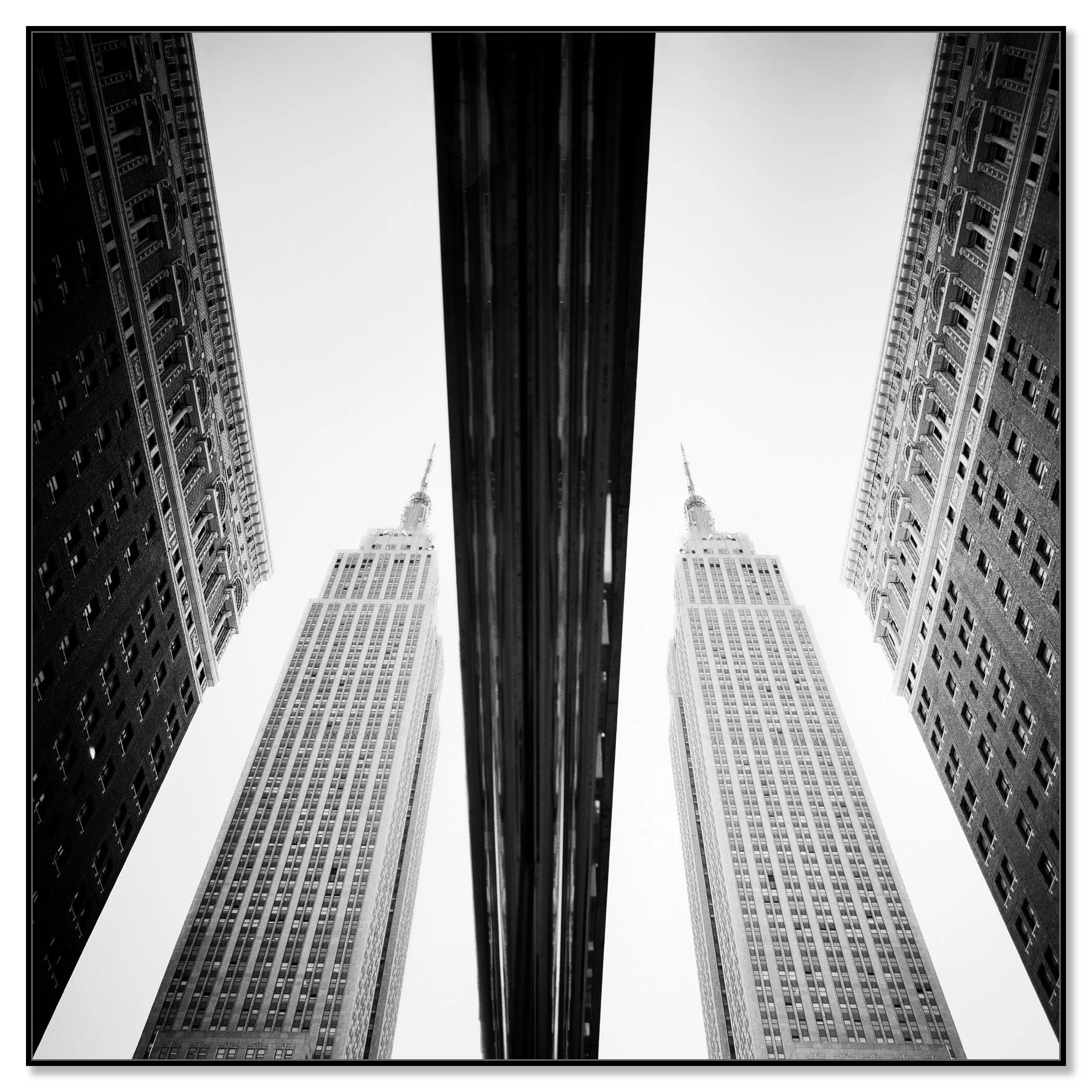 Low-angle black-and-white photograph of symmetrical skyscrapers in New York City – framed Artbox black