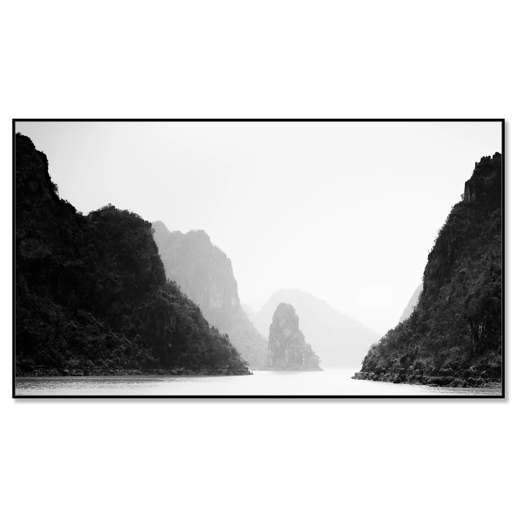 Black-and-white photo of calm water between steep limestone cliffs with misty mountains in the background – framed ArtBox black