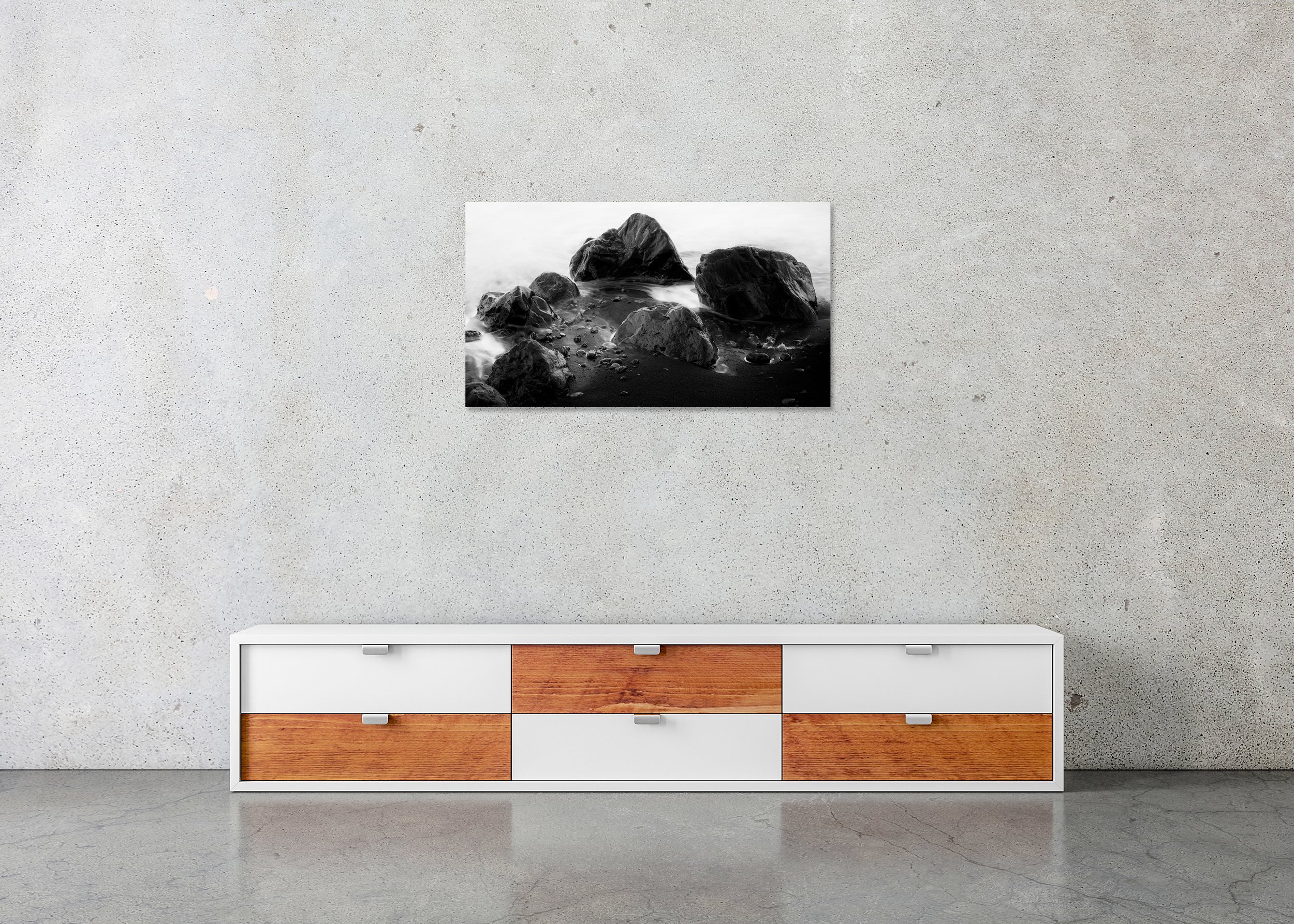 Monochrome coastal wall art print with dark shoreline rocks, smooth water and black sand, photo print mounted to Dibond, frameless