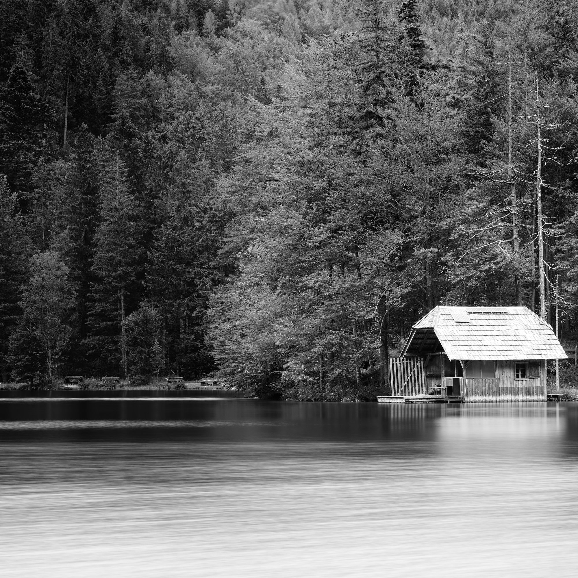 Detail of Wooden Boathouse Panorama showing the forest, boathouse and long-exposure water at Langbathsee by Gerald Berghammer.