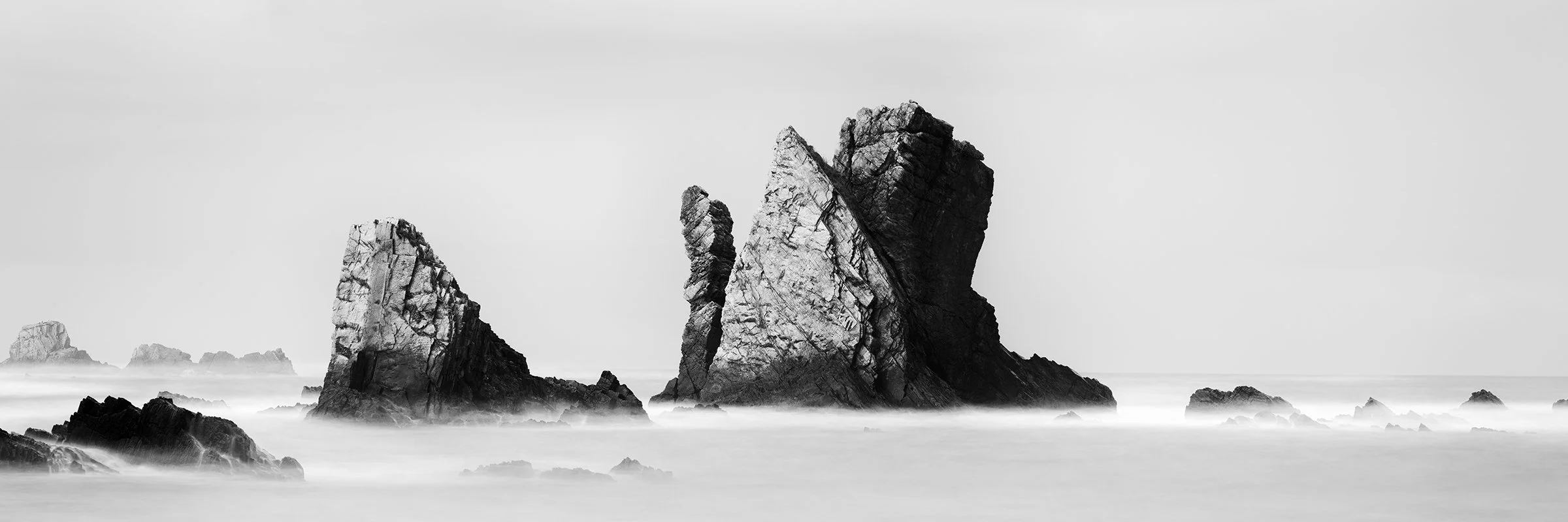 Monochrome seascape photography showing dramatic sea stacks off a rocky coast