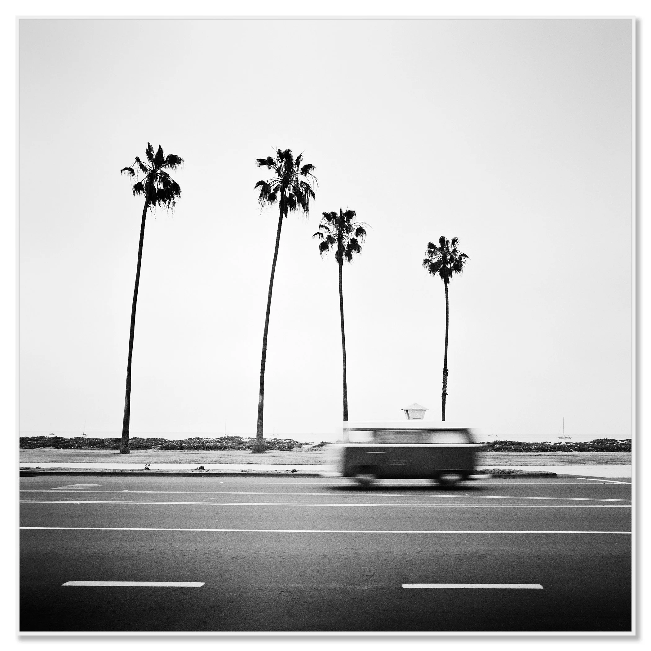 Black-and-white VW T2 bus with motion blur on a palm-lined coastal road in Santa Barbara, California – framed Artbox white