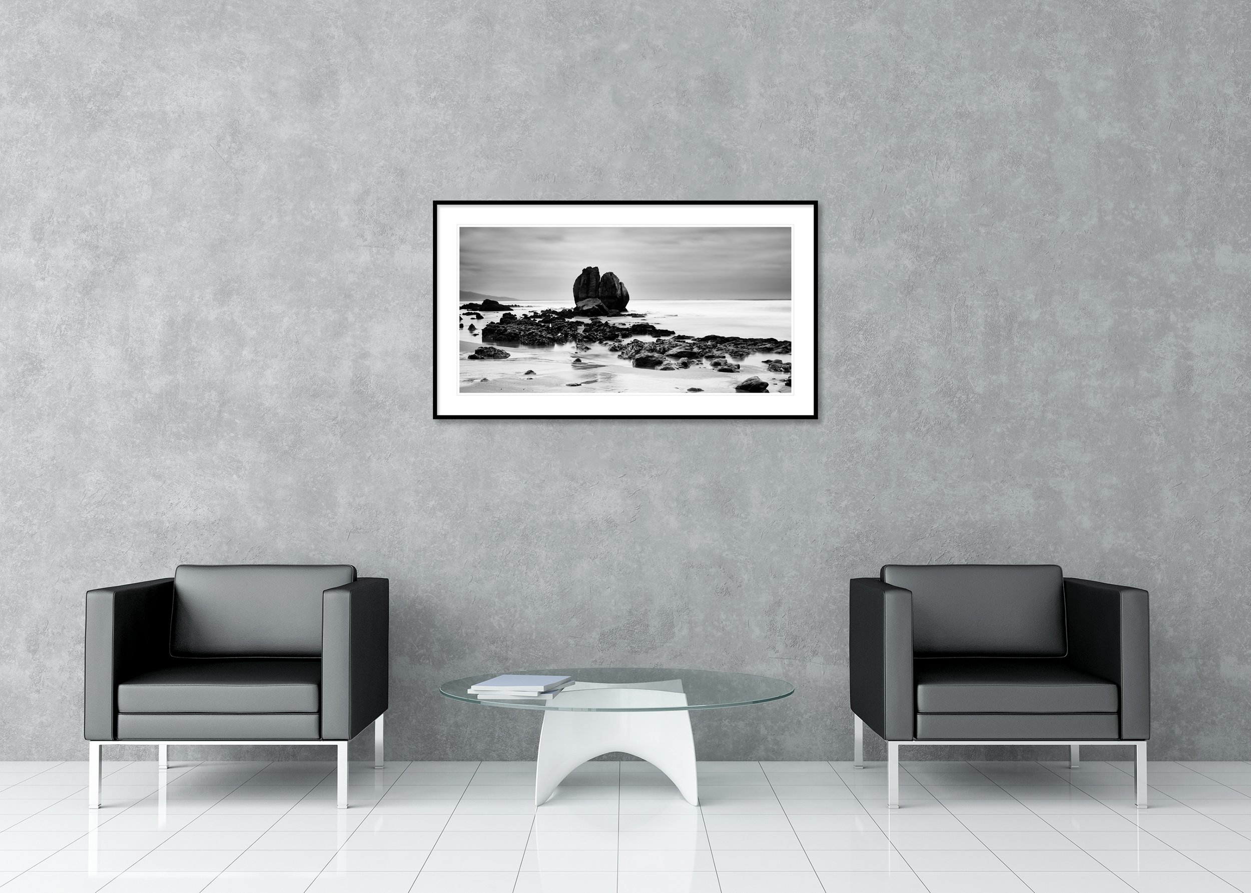Black and white long-exposure photo print of a rocky beach and sea under a cloudy sky, archival pigment print in a classic frame with a mount