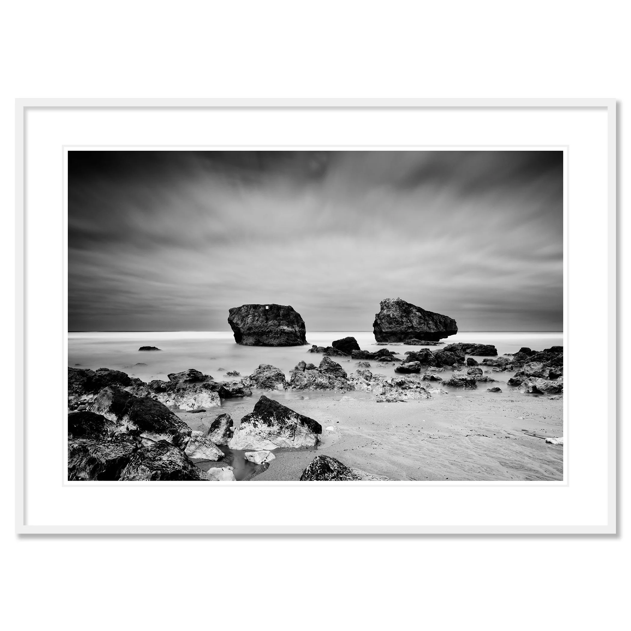 Gerald Berghammer - Black and white landscape photo. Rocky beach with two large rocks protruding from the water, cloudy sky, and smooth ocean surface. Classic framed white