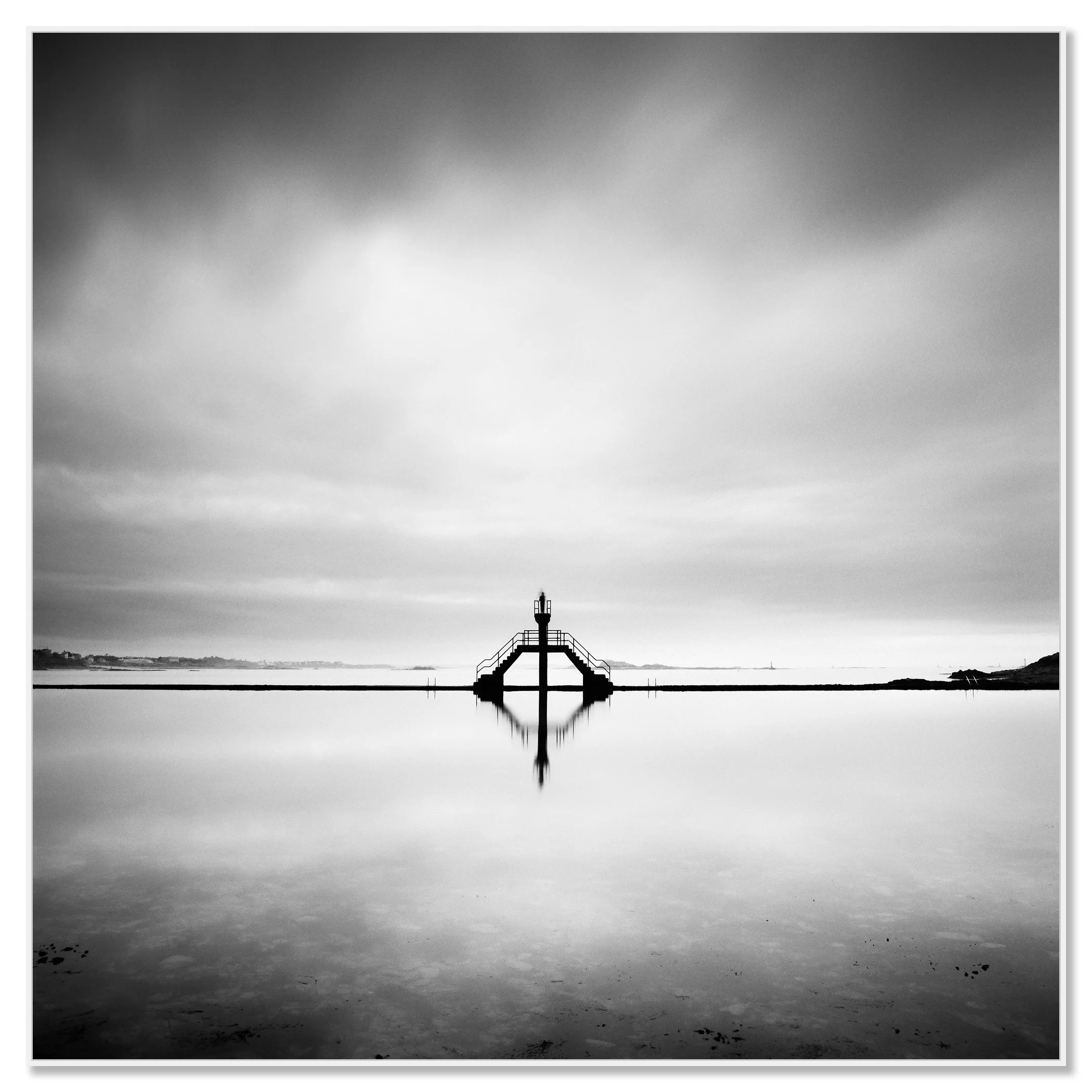 Black and white photograph of a small diving platform reflected in calm water under a cloudy sky, minimalist waterscape – framed ArtBox white