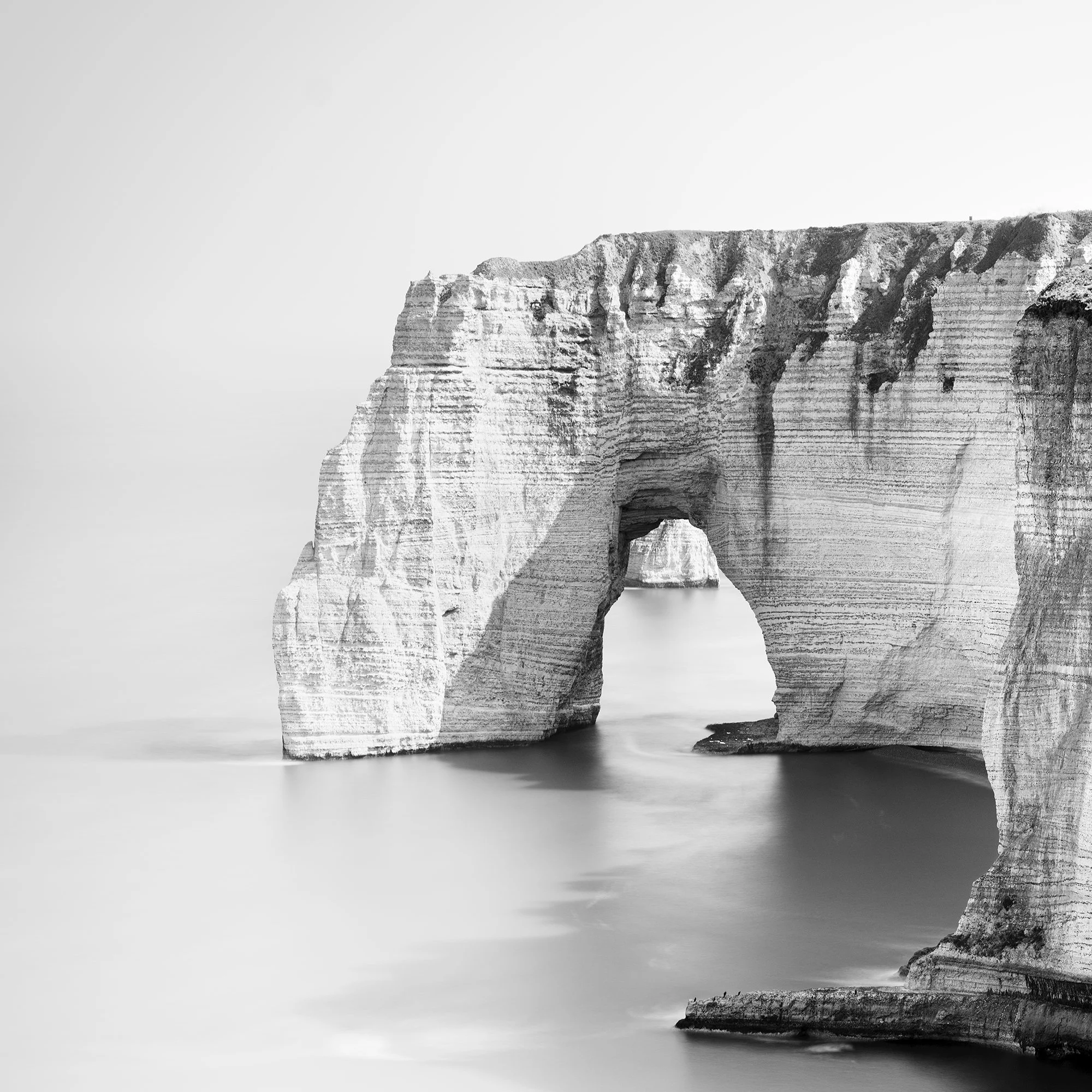 Detail of Alabaster Coast Study 1 by Gerald Berghammer, showing the chalk sea arch and layered cliffs of Étretat in black and white.